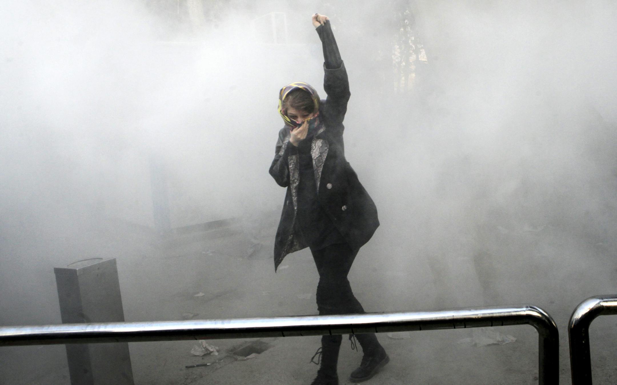 FILE - In this Saturday, Dec. 30, 2017 file photo, taken by an individual not employed by the Associated Press and obtained by the AP outside Iran, a university student attends a protest inside Tehran University while a smoke grenade is thrown by anti-riot Iranian police, in Tehran, Iran. Iranís top regional foes, Israel and Saudi Arabia, are both watching that countryís protests for signs they could lead to change. Iranís supreme leader has accused enemies of stoking the unrest.