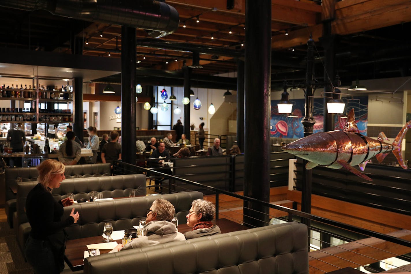 Dinners talked with a waitress as a metallic shark hung nearby in the dining room at the Octo Fishbar. ] ANTHONY SOUFFLE • anthony.souffle@startribune.com Restaurant review of Tim McKee's new Octo Fishbar photographed Friday, Feb. 23, 2018 in St. Paul, Minn.