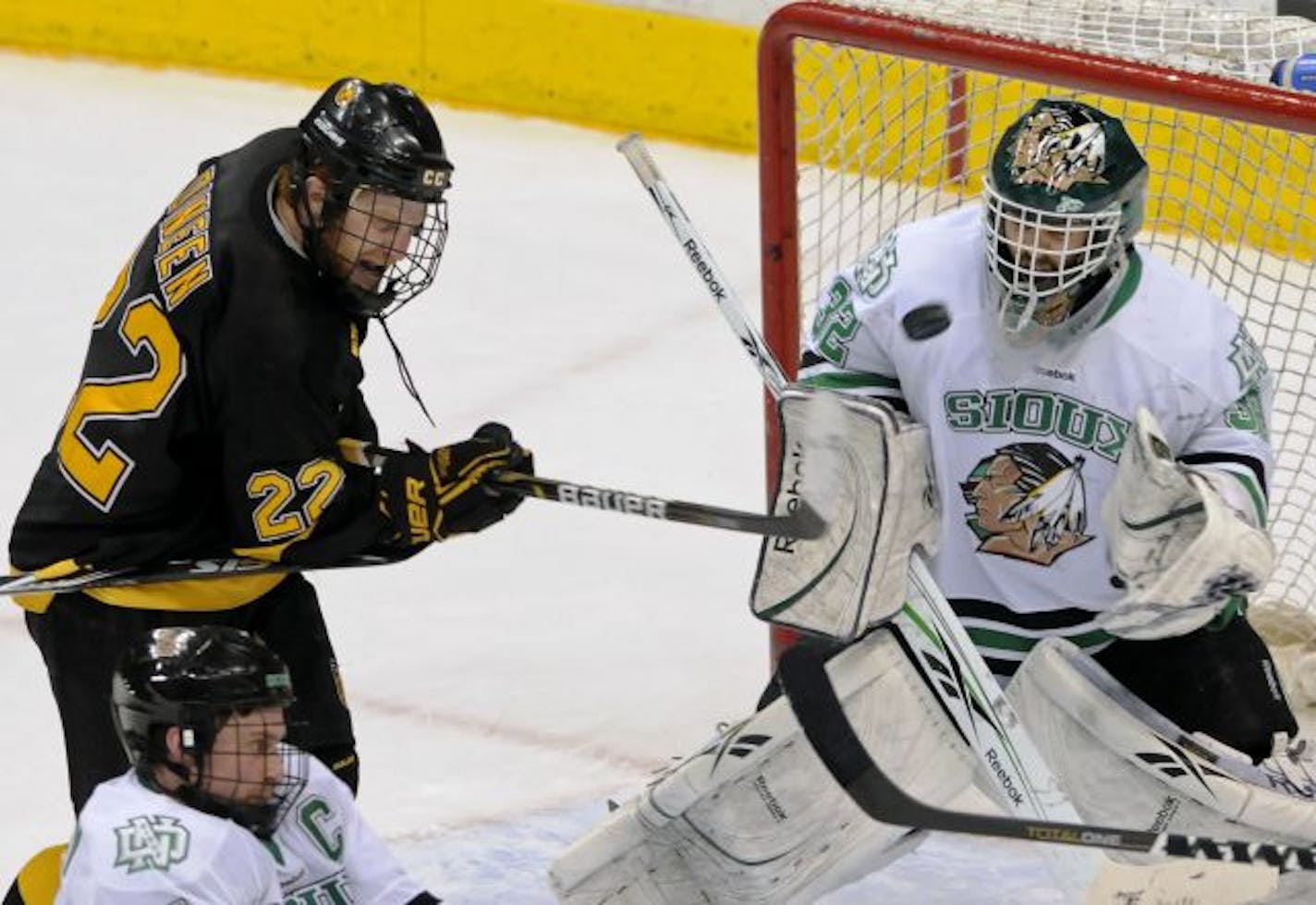 The puck heads toward North Dakota goalie Aaron Dell, right, before going over his head as Colorado College's Nick Dineen challenged the net in the third period of a WCHA Final Five college hockey game Friday, March 18, 2011 in St. Paul, Minn. At lower left is North Dakota's Chad Genoway. North Dakota won 4-3.