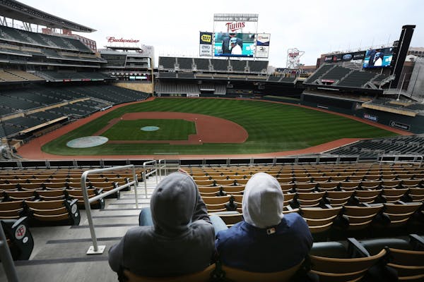 Twins fans Greyson Altermose, left, and his father, Trey Altermose, watched their team open the season against the Detroit Tigers on the big screen at