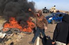 Demonstrators stand next to burning tires as armed soldiers and law enforcement officers assemble on Thursday, Oct. 27, 2016, to force Dakota Access p