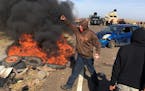 Demonstrators stand next to burning tires as armed soldiers and law enforcement officers assemble on Thursday, Oct. 27, 2016, to force Dakota Access p