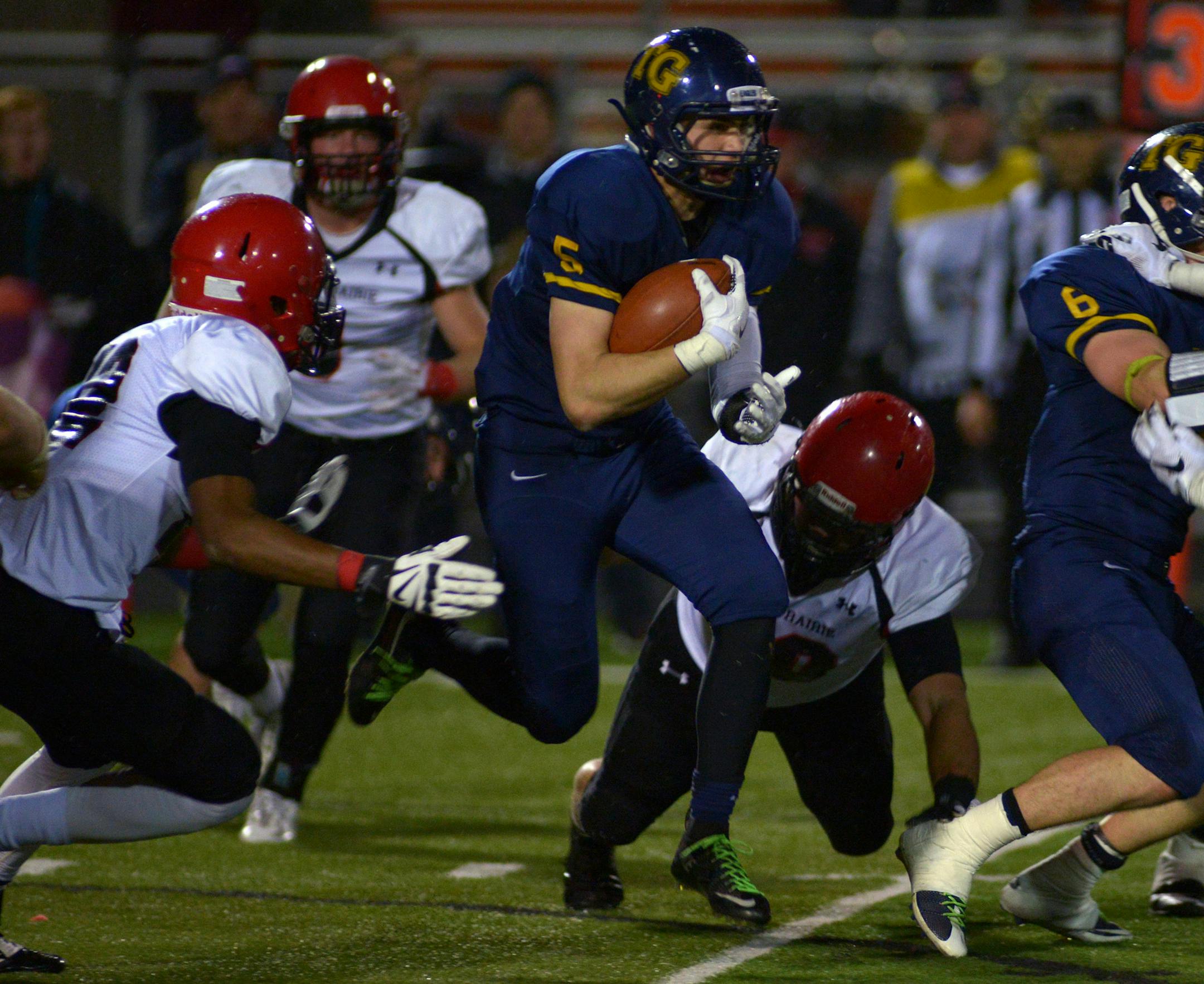 Totino-Grace junior Ivan Burlak carries the ball through Eden Prairie defense during the second half of the Class 6A state tournament quarterfinal game Friday night at Osseo High School. Totino-Grace's 27-13 victory over Eden Prairie sends them to the semifinal game Thursday, November 5 against Osseo. ] (SPECIAL TO THE STAR TRIBUNE/BRE McGEE) **Ivan Burlak (blue, 5)