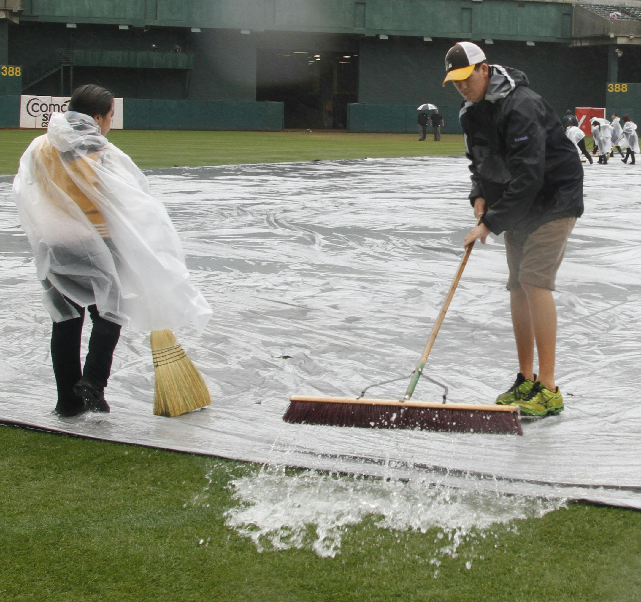 Grounds crew pushes water off the infield tarp before a baseball game between the Minnesota Twins and Oakland Athletics, Saturday, Sept. 21, 2013, in Oakland, Calif. (AP Photo/George Nikitin)
