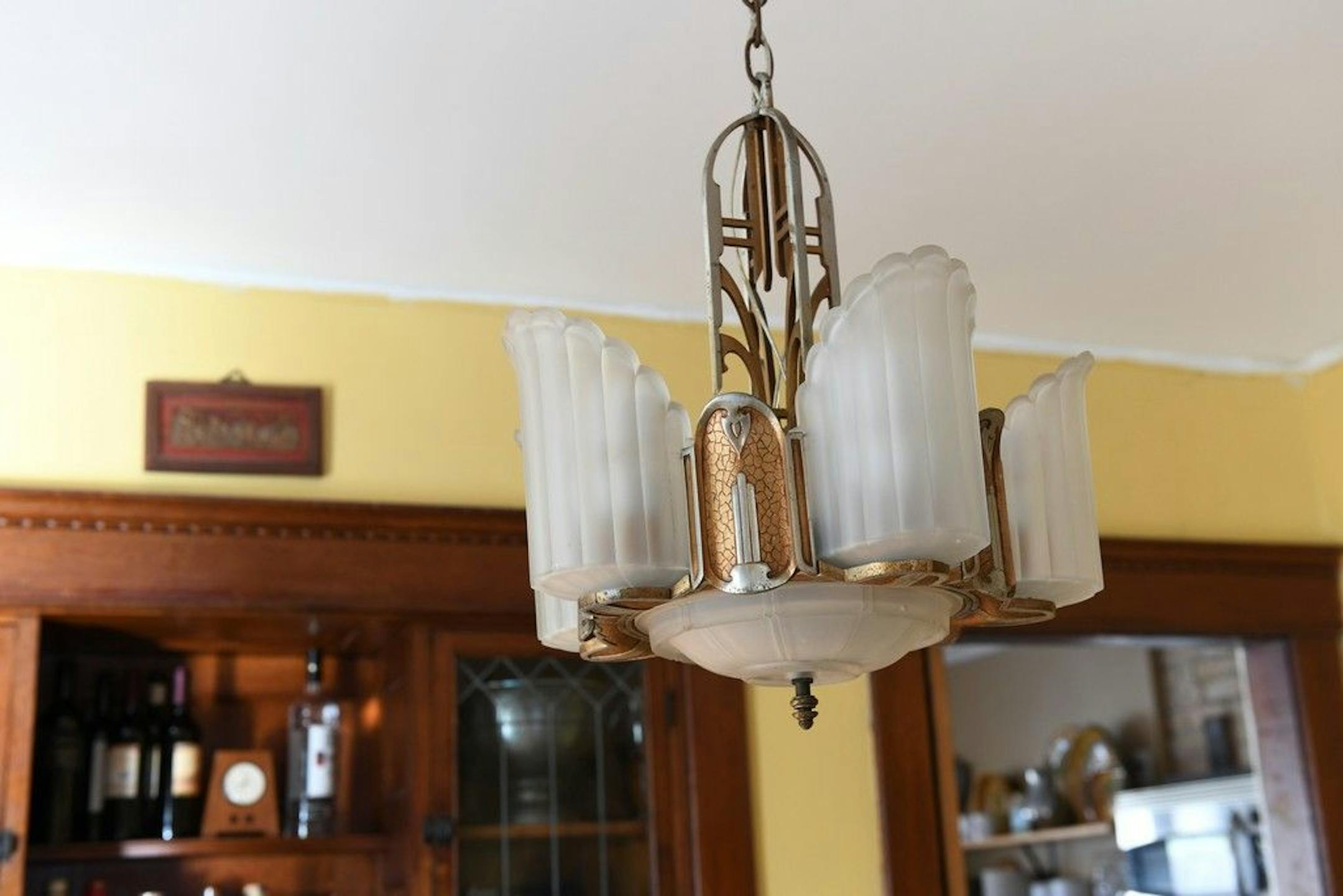A chandelier in front of a built-in buffet.