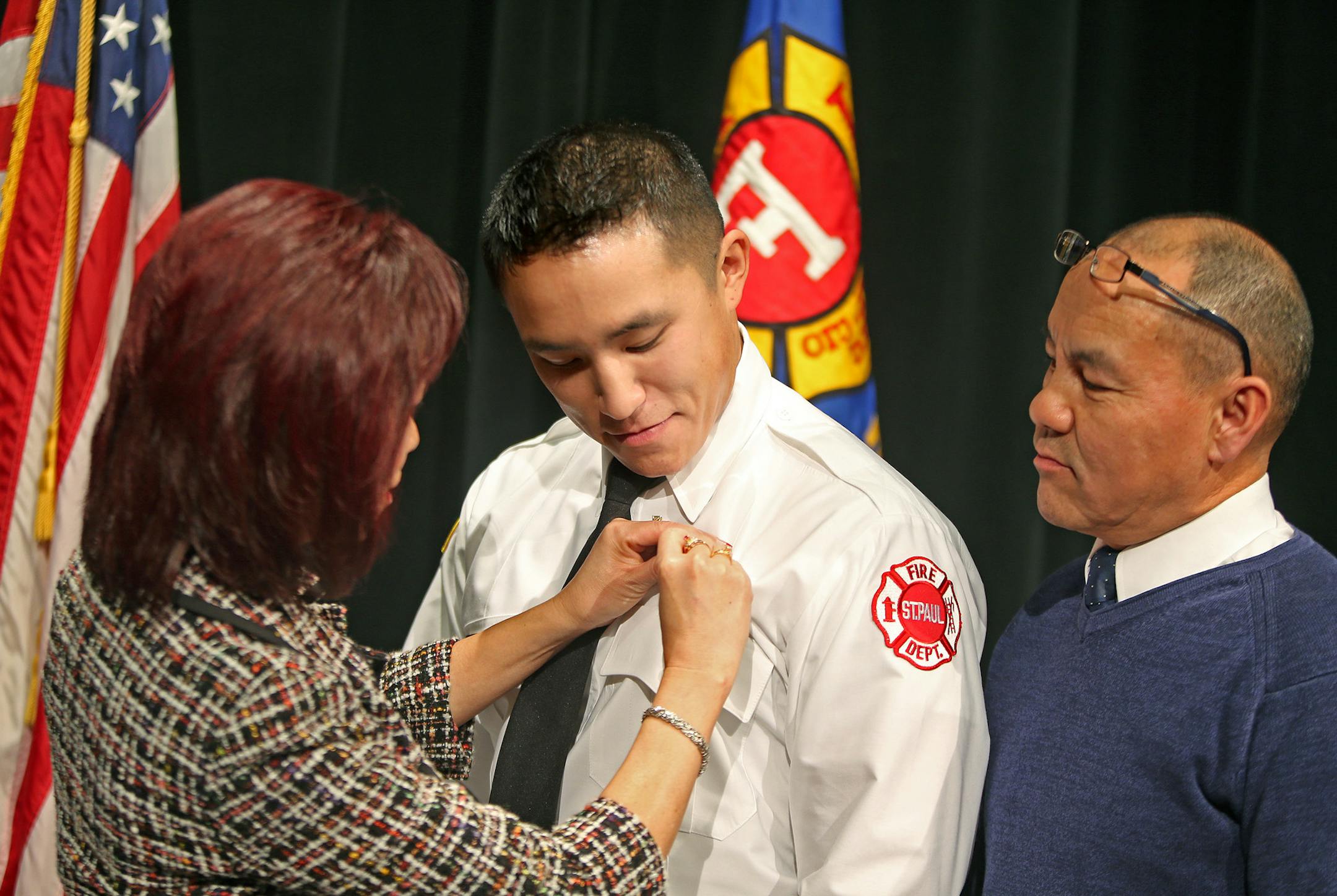 Pamela and David Lo pinned on their son's, Tou Lo, firefighter's badge at the St. Paul Fire Department's graduation ceremony at the Paul and Sheila Wellstone Center, Friday, January 3, 2014 in St. Paul, MN. (ELIZABETH FLORES/STAR TRIBUNE) ELIZABETH FLORES &#x2022; eflores@startribune.com