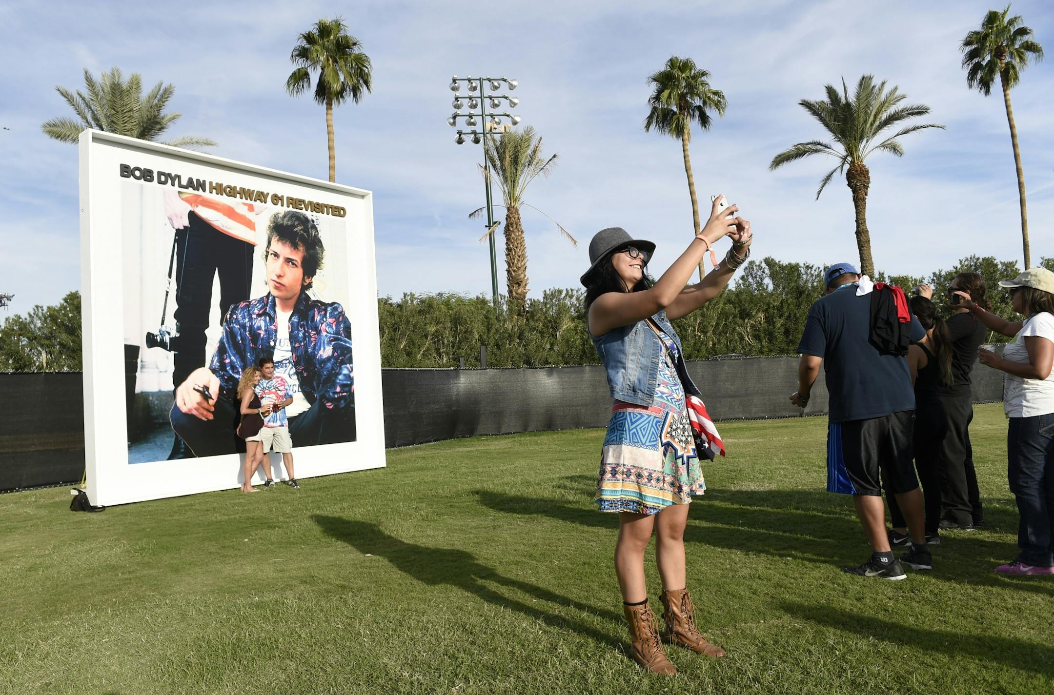Carla Chong of El Paso, Texas, shoots a selfie of herself in front of a billboard of Bob Dylan's album "Highway 61 Revisited" on day 1 of the 2016 Desert Trip music festival at Empire Polo Field on Friday, Oct. 7, 2016, in Indio, Calif.