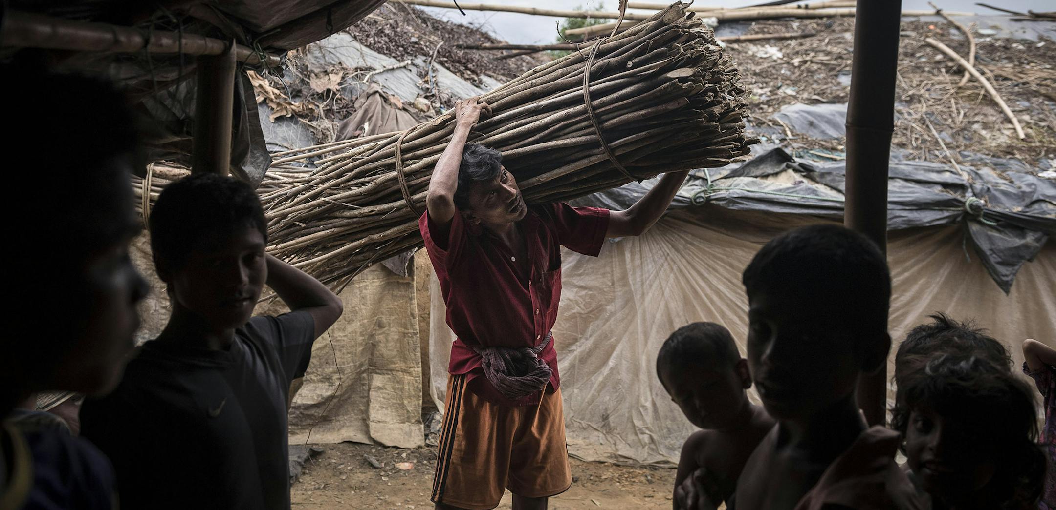 A Rogingya worker carries wood at the Kutupalong Refugee Camp in Teknaaf, Bangladesh, June 16, 2015. In 1992, hundreds of thousands of ethnic Rohingya fleeing a campaign of arson, rape and extrajudicial killing by the Burmese Army poured into Bangladesh where a multimillion-dollar people smuggling business has sent roots deep into impoverished corners of the country. (Sergey Ponomarev/The New York Times) ORG XMIT: MIN2015073017181269
