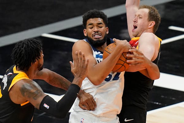 Minnesota Timberwolves center Karl-Anthony Towns, center, grabs a rebound as Utah Jazz's Derrick Favors, left, and Joe Ingles defend during the second