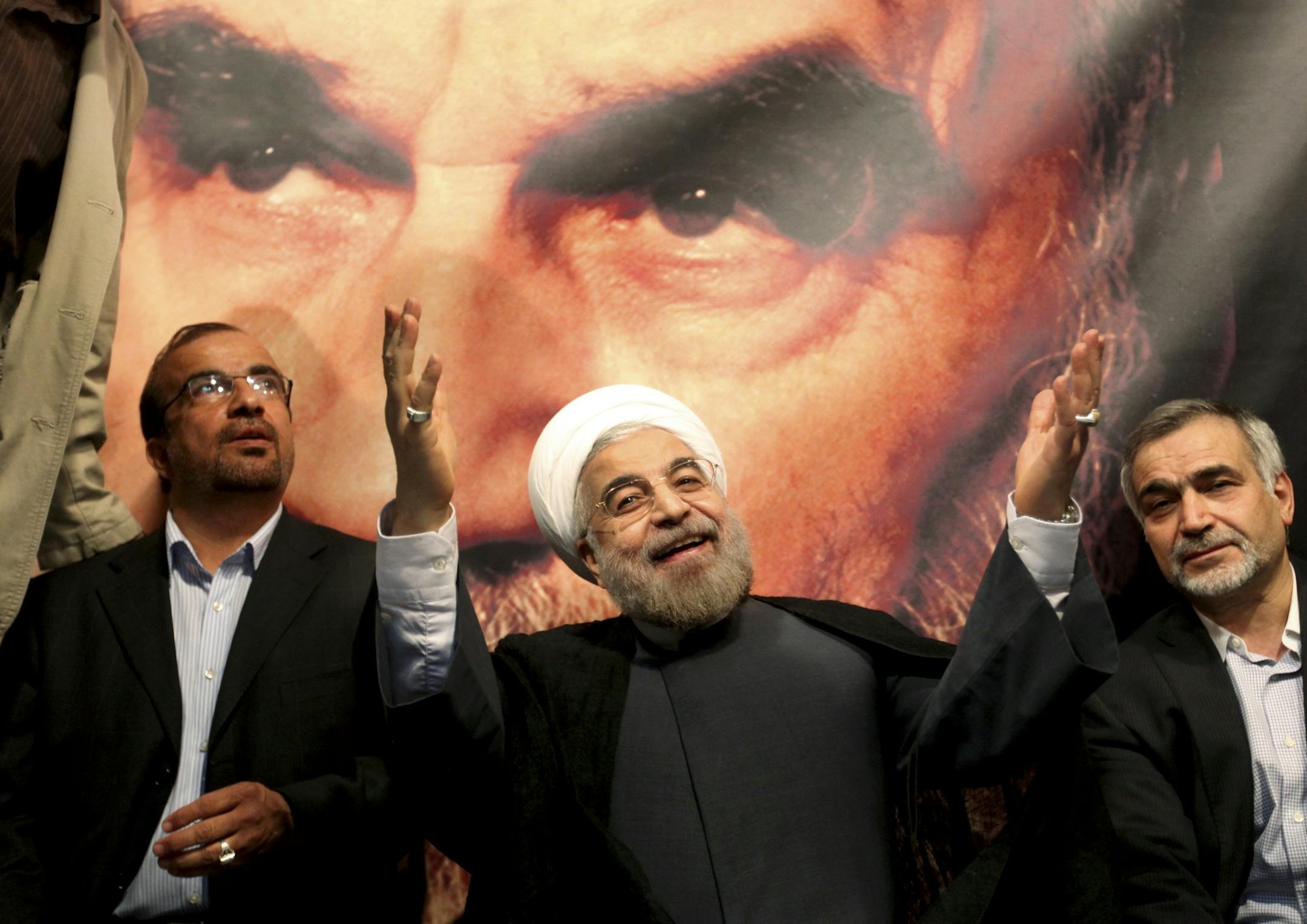 In front of a portrait of the late Iranian revolutionary founder Ayatollah Khomeini, presidential candidate Hasan Rowhani, a former top nuclear negotiator, center, gestures to his supporters at a rally in Tehran, Iran, Saturday, June 1, 2013.