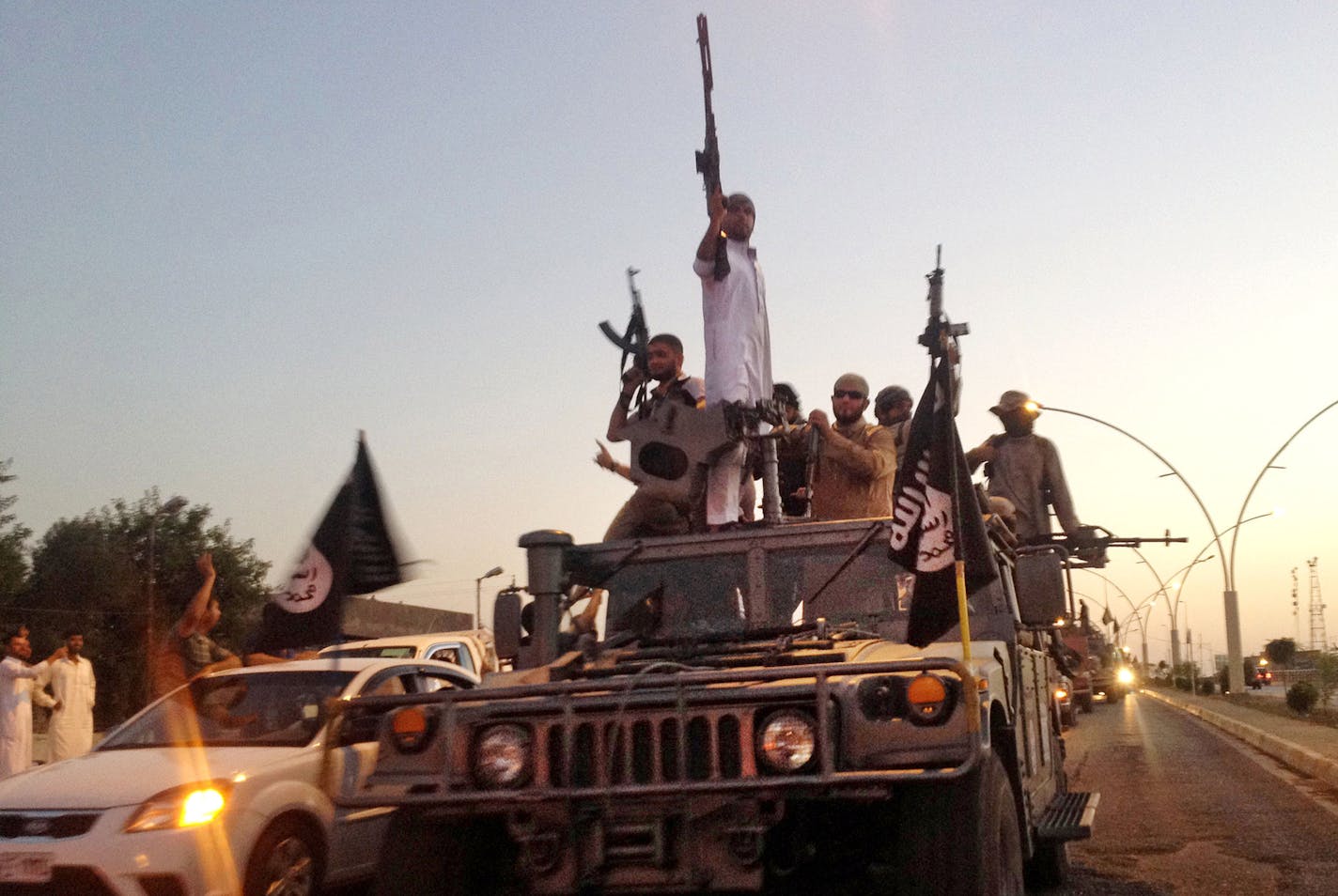 FILE - In this photo taken Monday, June 23, 2014, fighters from the Islamic State group parade in a commandeered Iraqi security forces armored vehicle down a main road at the northern city of Mosul, Iraq. An independent monitoring group says some bombings carried out by the U.S.-led coalition targeting the Islamic State group likely have killed hundreds of civilians. The coalition had no immediate comment on the report released Monday, Aug. 3, 2015. (AP Photo, File) ORG XMIT: CAI110