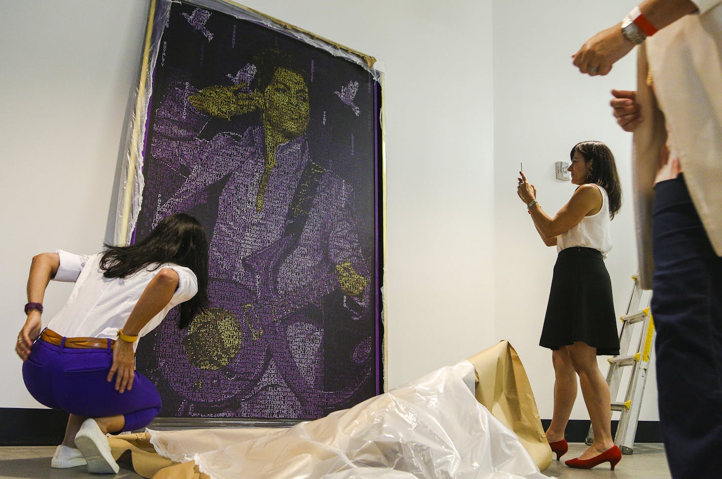 Members of the Minnesota Vikings staff take a closer look and photograph "Purple Reign" after its unveiling. ] Timothy Nwachukwu &#x2022; timothy.nwachukwu@startribune.com "Purple Reign," a multidimensional acrylic paint on canvas portrait of Prince by artist Nicholas Schleif is hung inside the Pentair gate at U.S. Bank Stadium on Wednesday, July 20, 2016 in Minneapolis. The portrait is composed of Prince's lyrics to form elements including three doves, the Minneapolis skyline, a paisley pattern