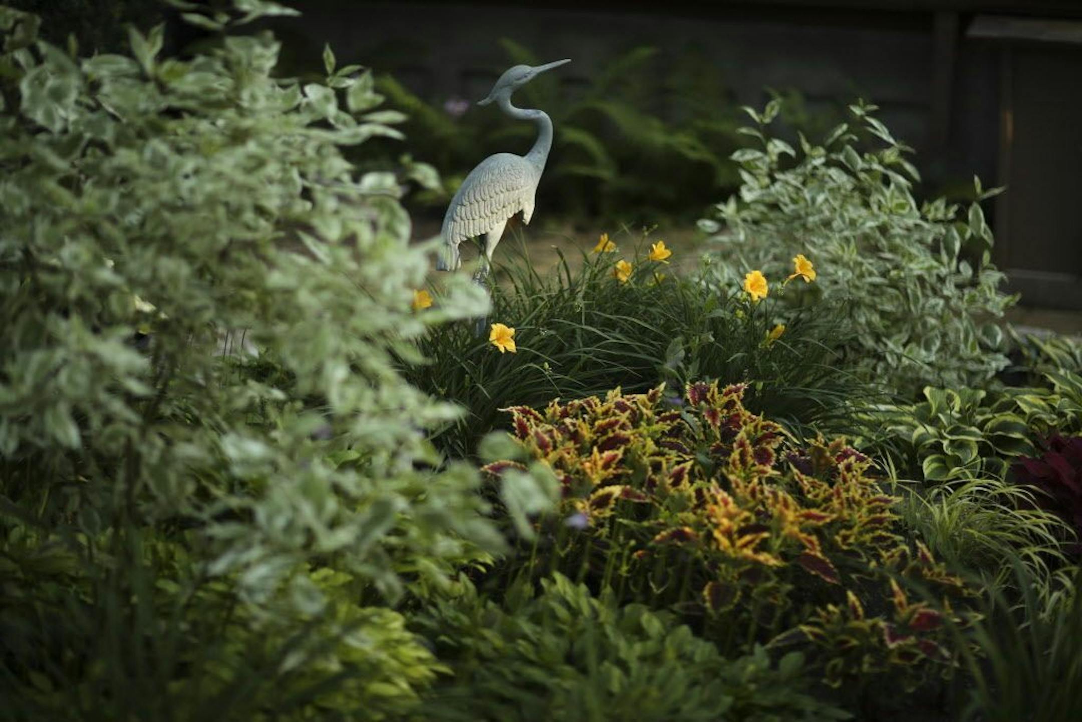 A crane sculpture highlights a backyard garden bed.