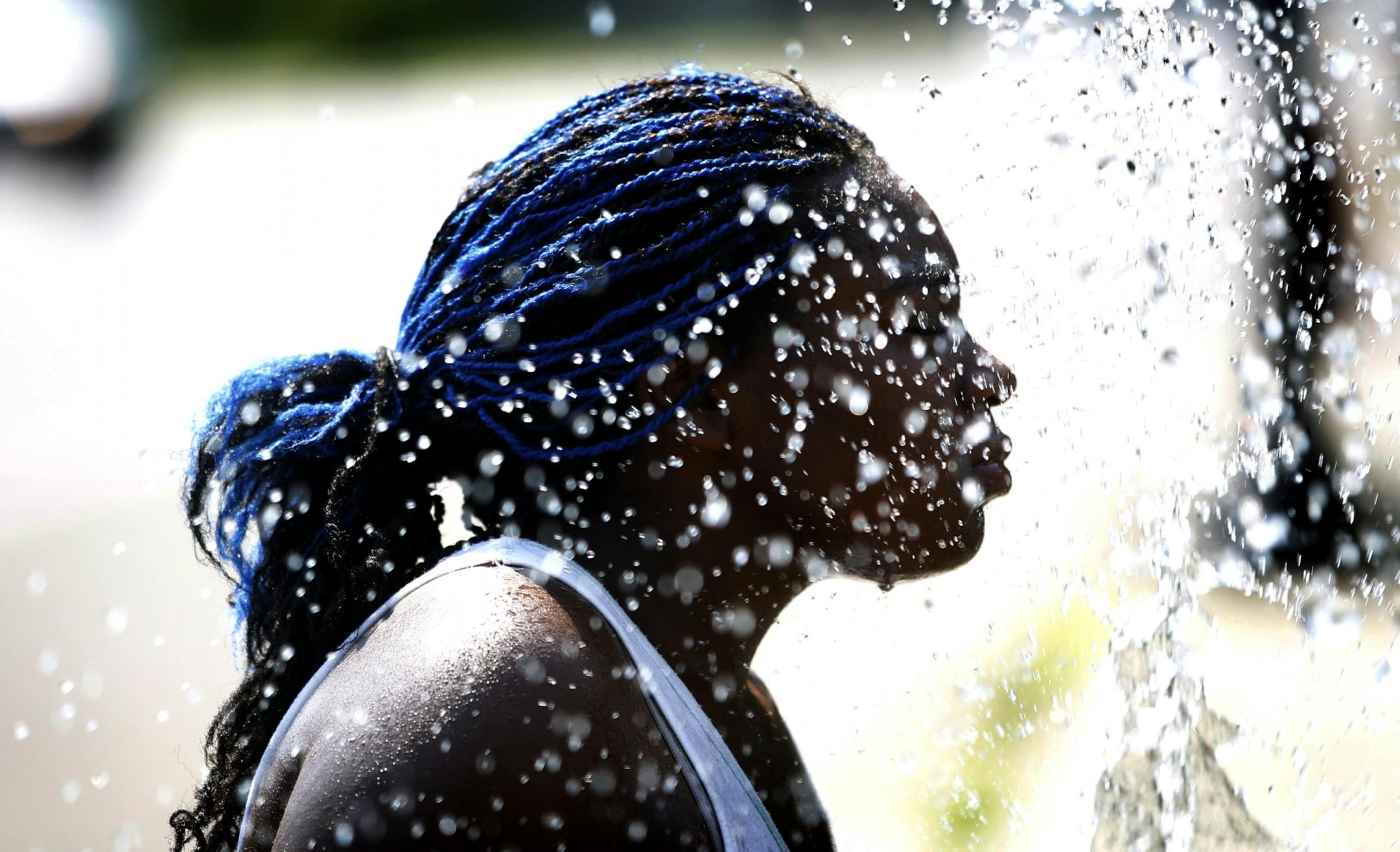 Shanetta Jones, 18, cooled off with a splash from the water hose in the 1600 block of Golden Valley Road on Monday.