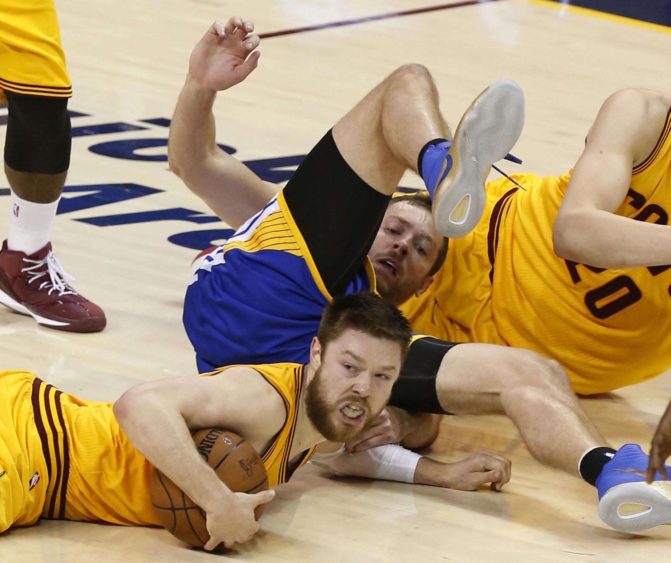 Cleveland Cavaliers guard Matthew Dellavedova, bottom, and Golden State Warriors forward David Lee go to the floor for a loose ball during the second half of Game 3 of basketball's NBA Finals in Cleveland, Tuesday, June 9, 2015. (AP Photo/Paul Sancya)