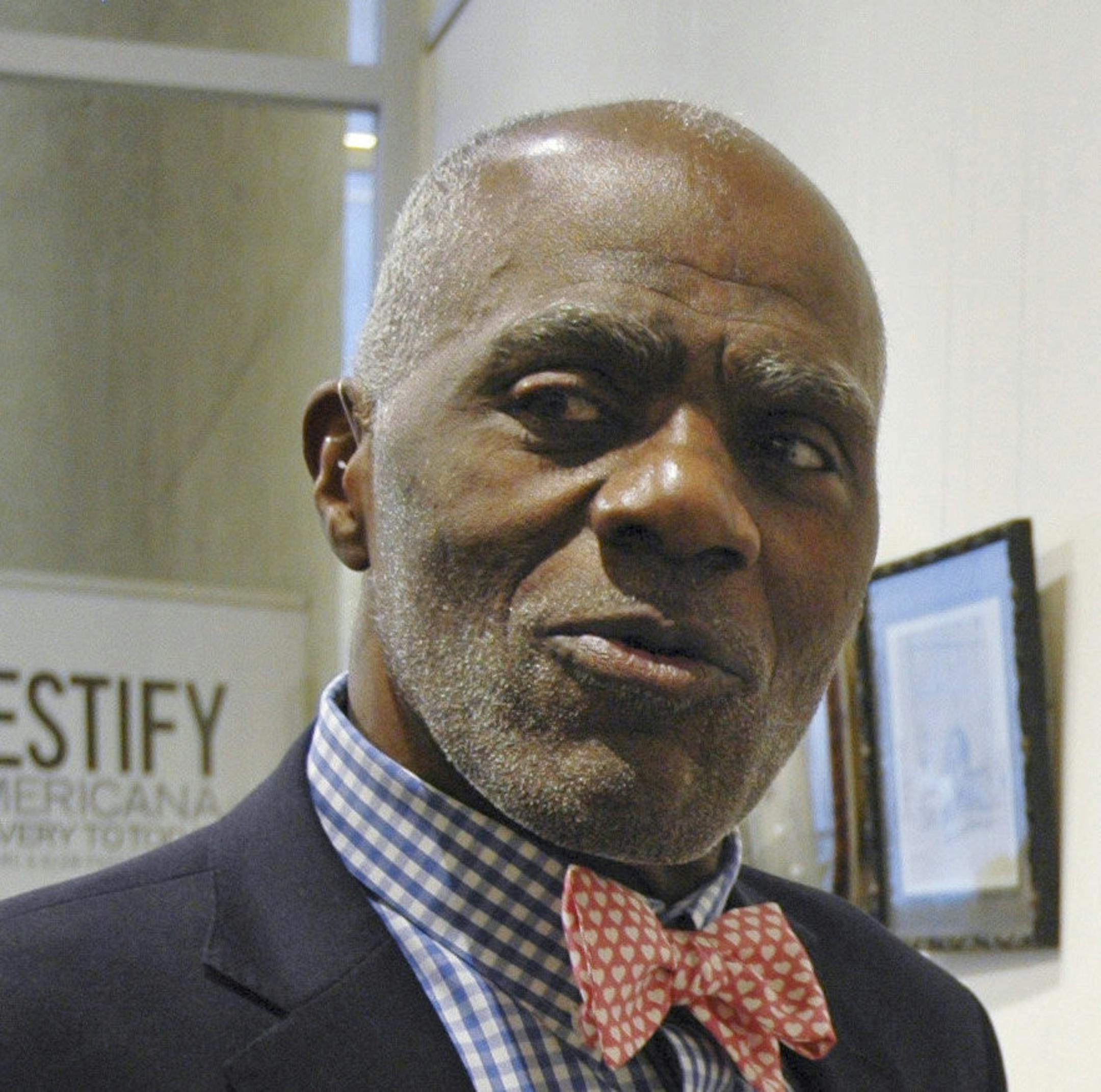 In this Jan. 11, 2018 photo, Alan Page, NFL Hall of Famer and retired Minnesota Supreme Court justice, stands in Minneapolis. by a photo of black babies labeled "Alligator Bait." It is among the artifacts of slavery and segregation collected by Page and his wife, Diane Sims Page. They went on display at the Minneapolis Central Library this month in time for Super Bowl visitors and thousands of other people expected to flock to downtown for the festivities. (AP Photo/Steve Karnowski)