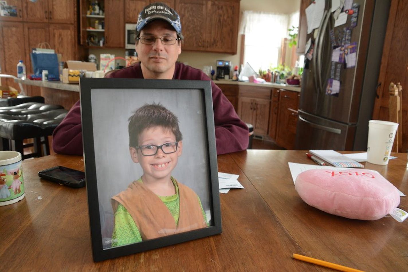 Alan Geisenkoetter Sr. at his family's dining room table looks at a photo of his son, Alan Jr., on Feb. 2, 2018.