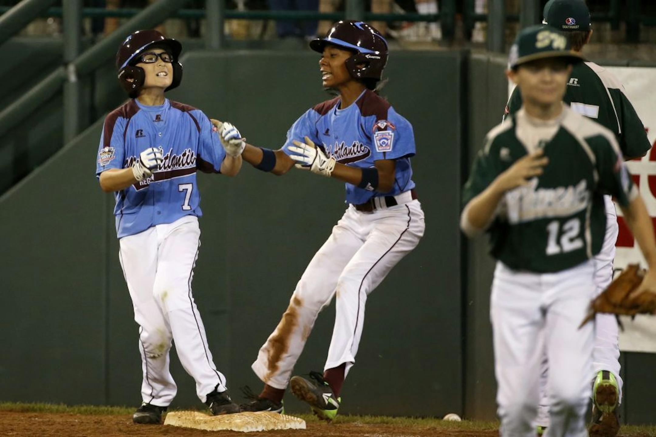 Philadelphia's Tai Shanahan (7) celebrates his walk-off single with teammate Mo'ne Davis, center, as Pearland pitcher Landon Donley (12) runs off the field during the sixth inning of a baseball game against Pearland in United States pool play at the Little League World Series tournament in South Williamsport, Pa., Sunday, Aug. 17, 2014. Philadelphia won 7-6. (AP Photo/Gene J. Puskar