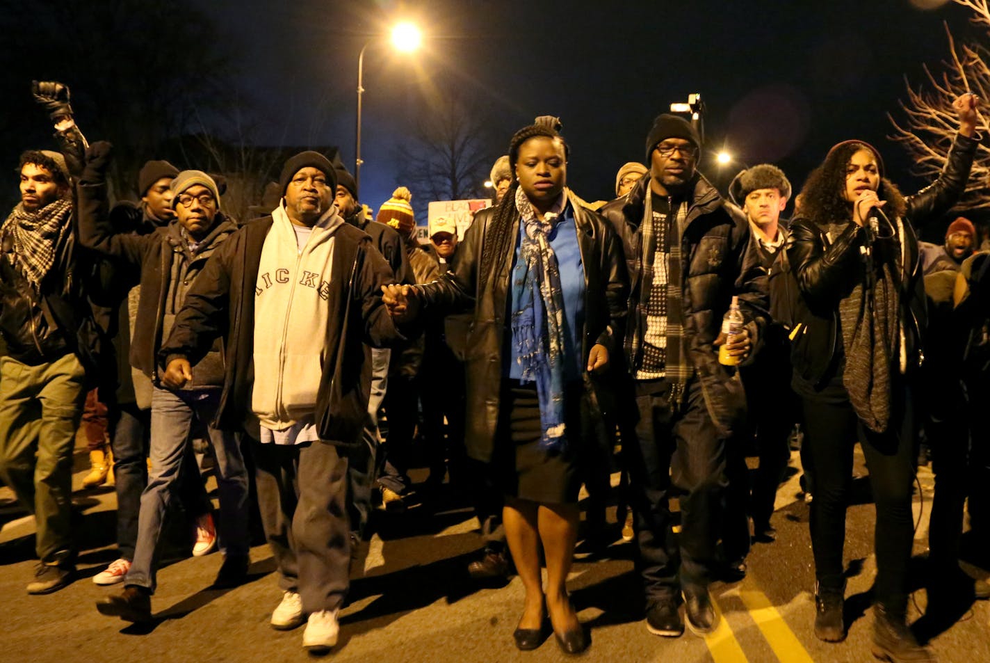 Nekima Levy-Pounds, center, with Jamar Clark&#x2019;s father, James Hill, to her right and Mica Grimm, far right, led marchers to the site where Clark was shot.