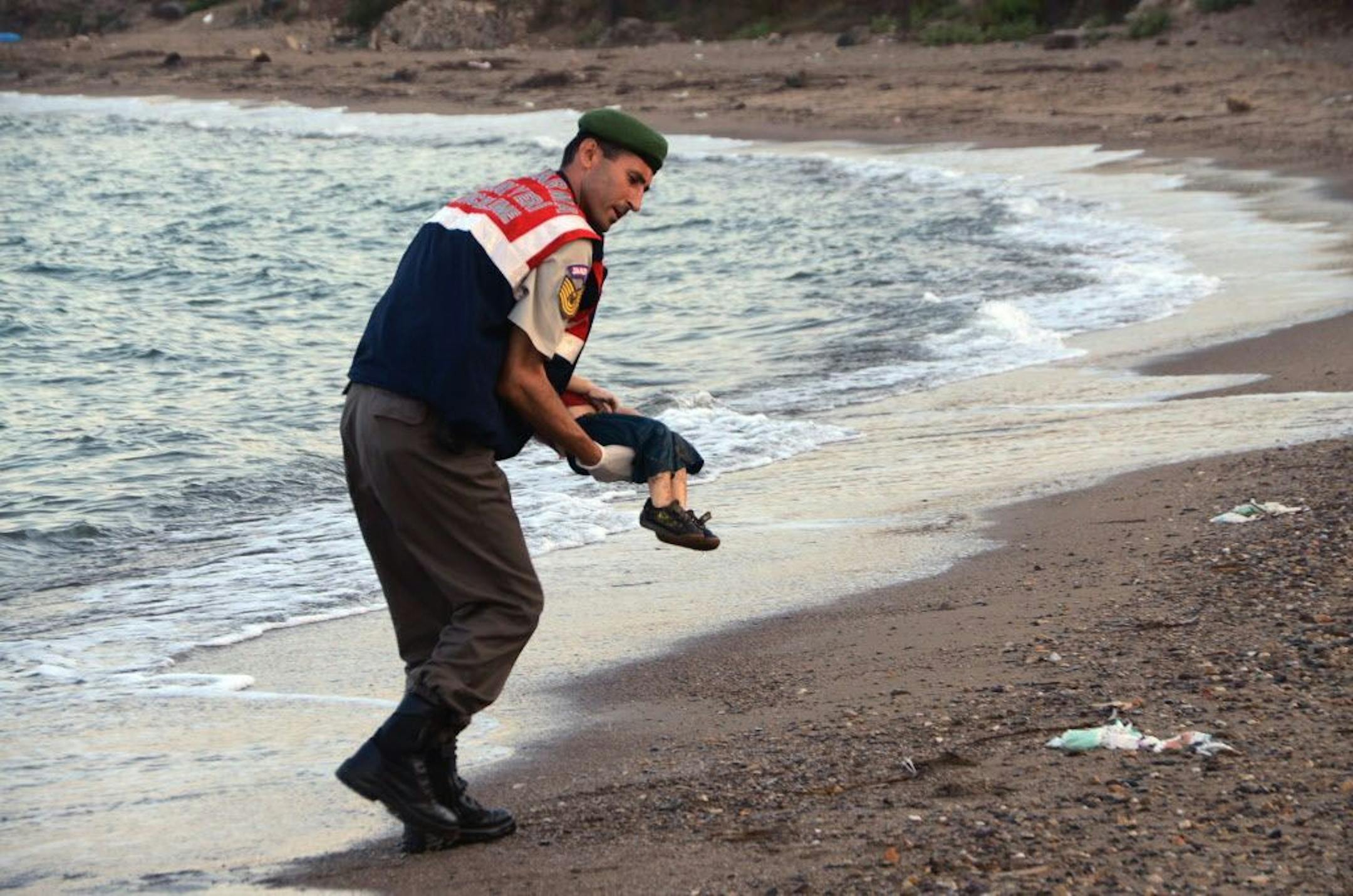 A paramilitary police officer carries the lifeless body of Aylan Kurdi, 3, after a number of migrants died aafter boats carrying them to the Greek island of Kos capsized.
