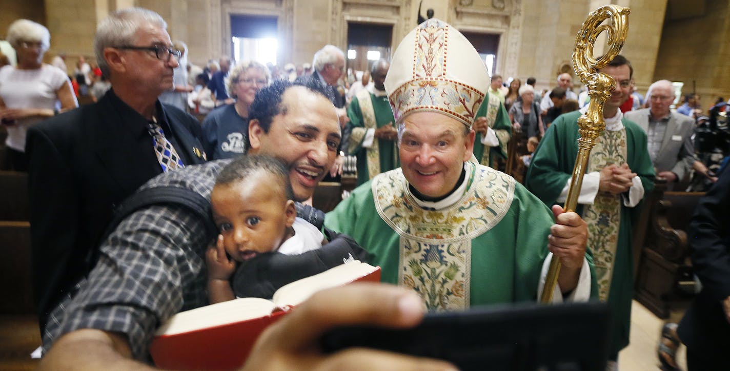 Aime held his son Raphael as they took a selfie with Archbishop Bernard Hebda who greeted parishioners after celebrating his first mass at the St. Paul Cathedral Sunday July 12, 2015 in St. Paul MN. ] Jerry Holt/ Jerry.Holt@Startribune.com