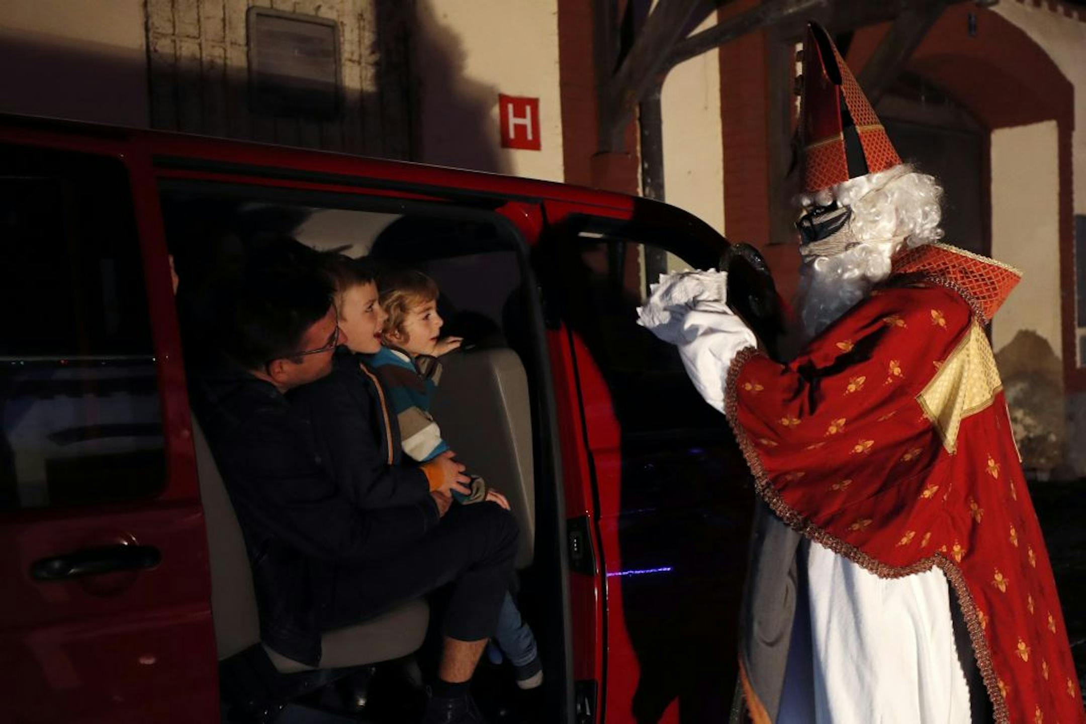 A member of the new circus company Cirk La Putyka, dressed as St. Nicholas, reacts with people driving through with their cars during a performance in Prague, Czech Republic, Saturday, Dec. 5, 2020. On the eve of St. Nicholas, Czechs traditionally celebrate by dressing up as Devils, Angels and St. Nicholas, and visiting children in their homes handing out small presents, coal, potatoes or other gifts. Due to the government's restrictive measures usual traditions would be impossible. A new circus