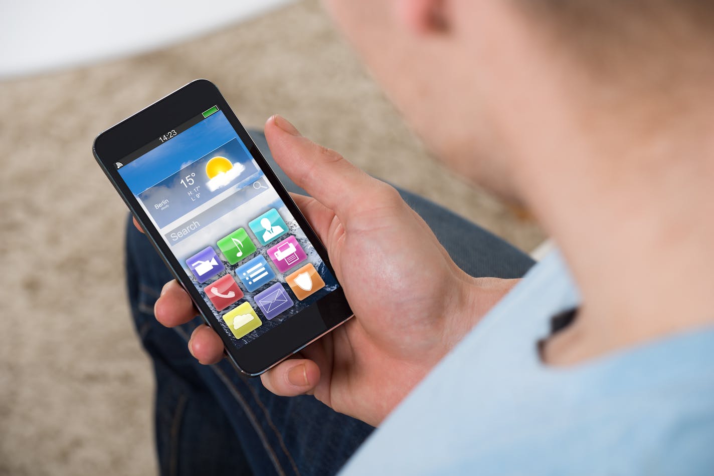 High angle view of man holding smartphone with colorful application icons at home