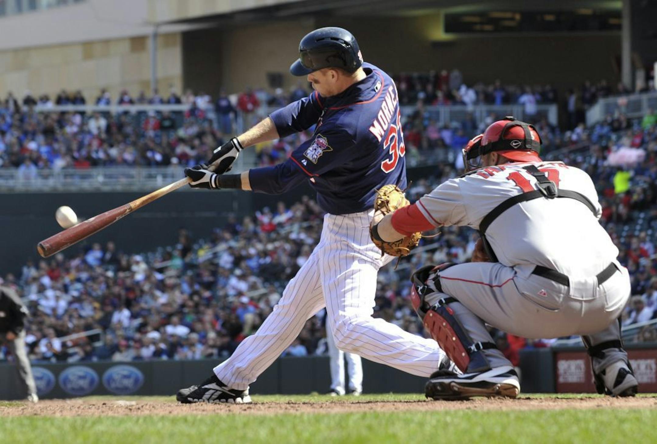 Minnesota Twins' Justin Morneau hits a two-run home run off Los Angeles Angels relief pitcher Rich Thompson in the eighth inning of a baseball game Thursday, April 12, 2012, in Minneapolis. Catching is Angels' Chris Iannetta. The Twins won 10-9.