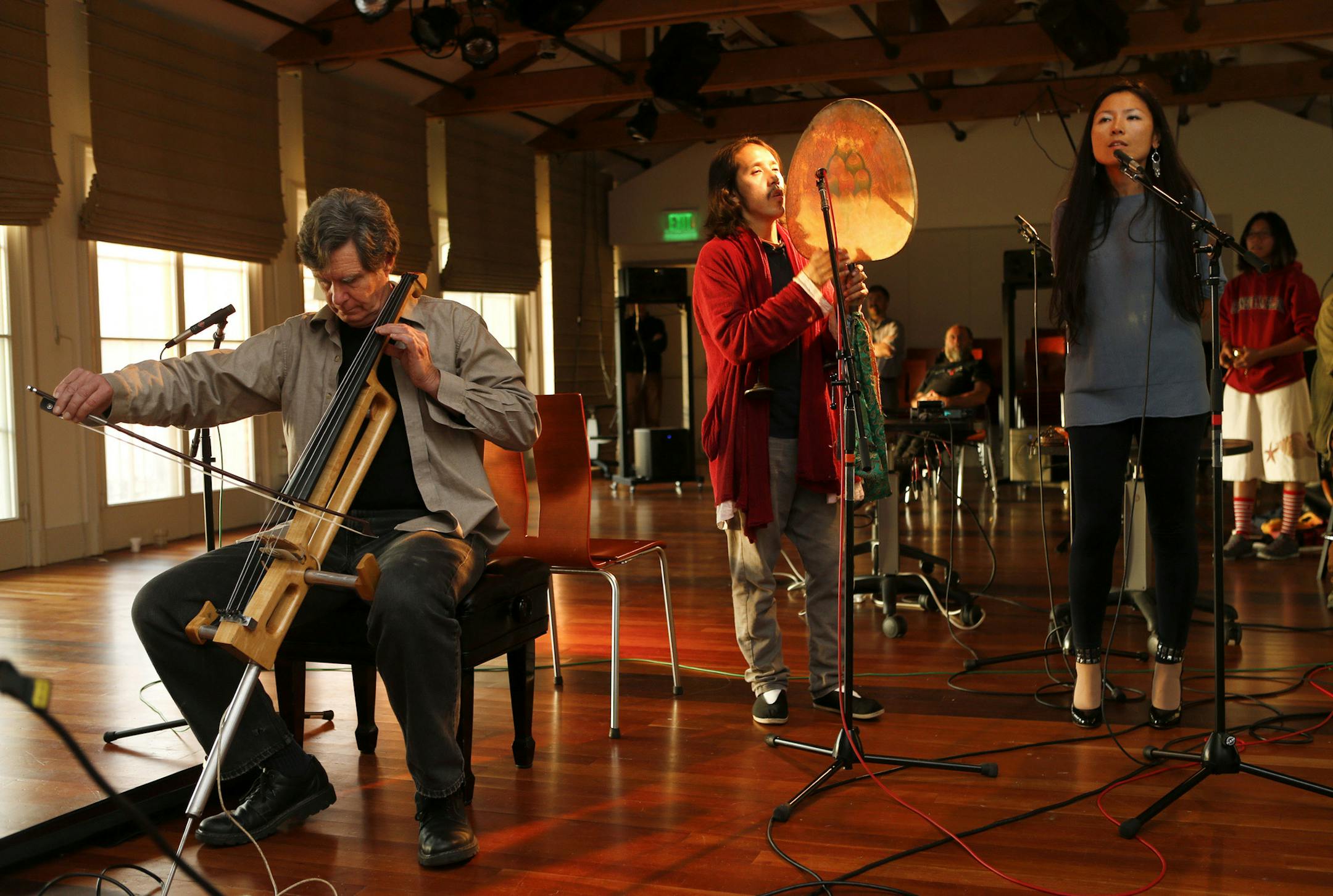 Chris Chafe, left, director of the Center for Computer Research in Music and Acoustics at Stanford University, plays his handmade electric cello with singers Reshi Tsering Tan, center, and Cecilia Wu, right, along with musicians in Virginia Tech and Santa Barbara via the internet in Stanford, Calif., on November 17, 2014. (Nhat V. Meyer/Bay Area News Group/TNS)
