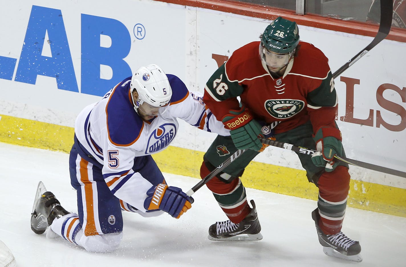 Edmonton Oilers defenseman Mark Fraser (5) and Minnesota Wild left wing Matt Moulson (26) tangle as they chase the puck during the first period of an NHL hockey game in St. Paul, Minn., Tuesday, March 11, 2014. (AP Photo/Ann Heisenfelt)