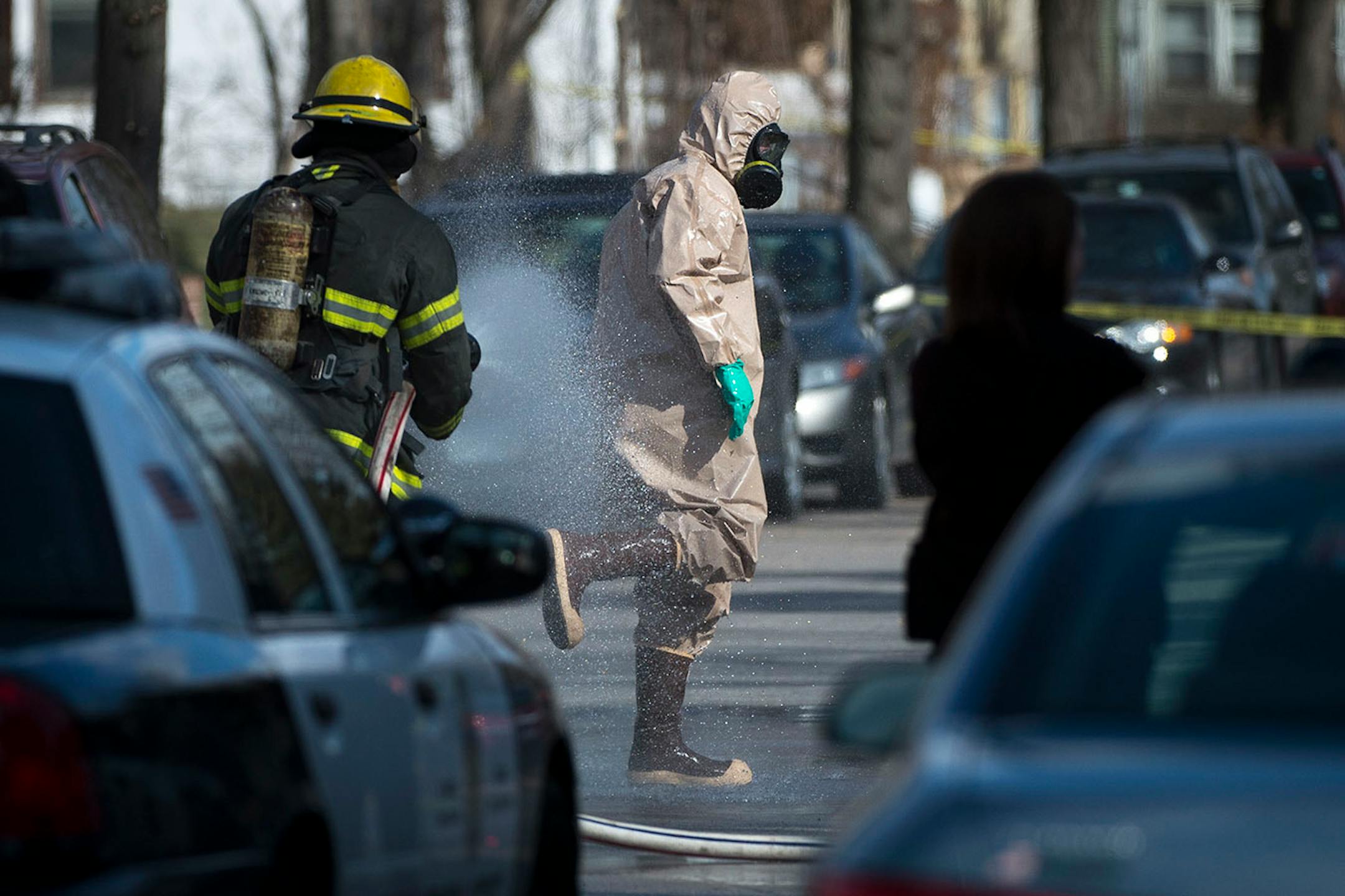 A hazardous material worker is hosed down by a member of the Minneapolis Fire Department after leaving a residence in the Marcy Holmes neighborhood of Minneapolis on the 500 block of 6th Street Southeast on Friday, April 10, 2015.