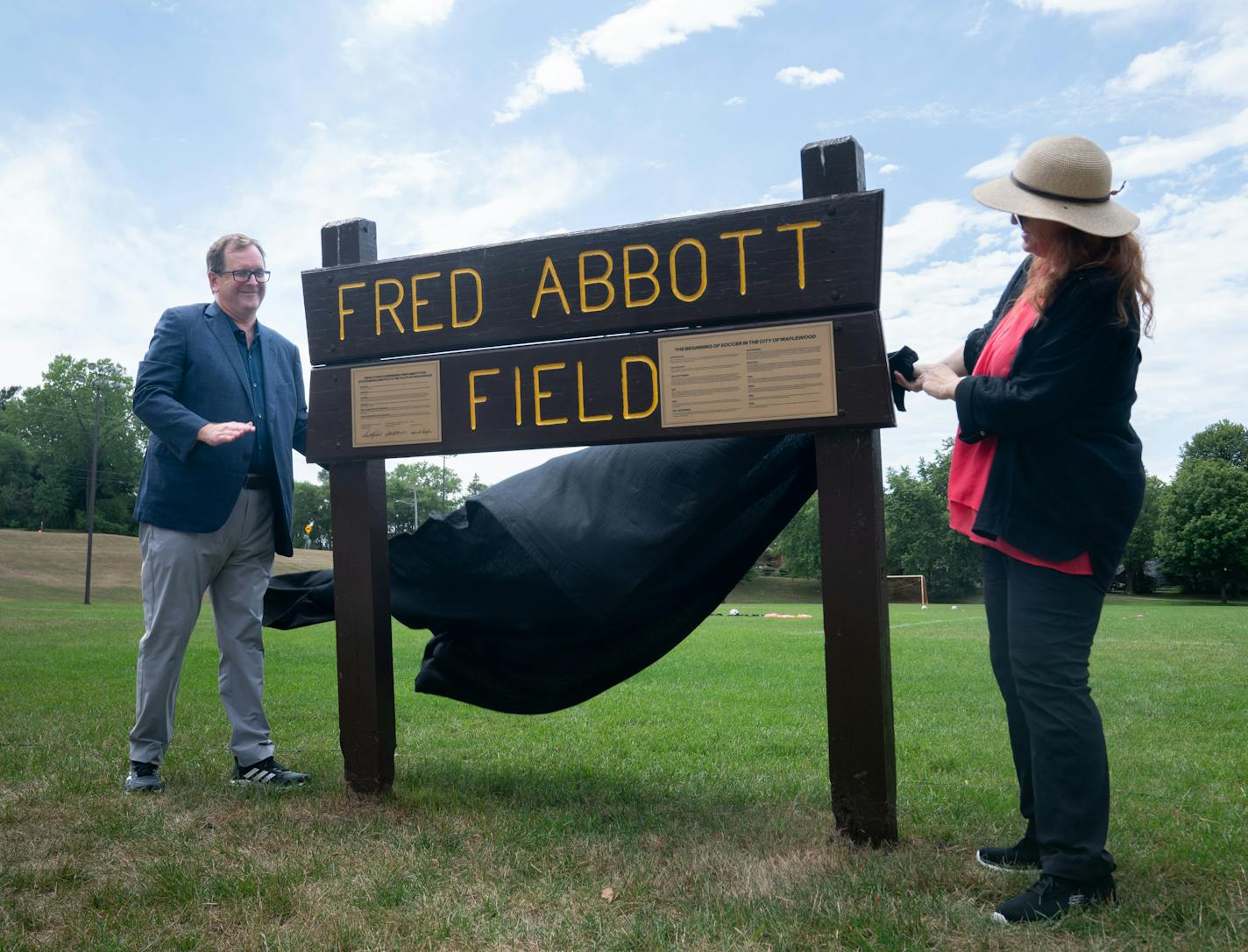 Major League Soccer President and Deputy Commissioner Mark Abbott, a native of Oakdale, Minn., unveils the updated sign with his sister Heather Abbott during the Fred Abbott Field rededication ceremony for their father.