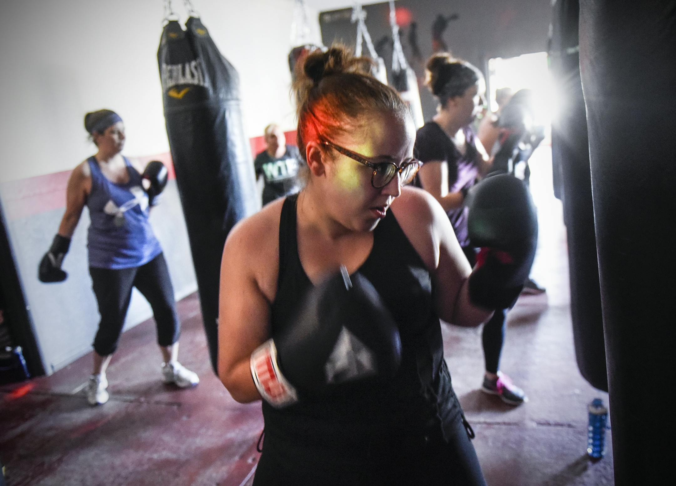 Class members punch under colored strobe lights during a Spicy Boxing class Tuesday, May 22, 2018, at We Thrive Fitness in Monticello, Minn. The high-energy workout mixes punching bag and Latin dance moves. (Dave Schwarz/St. Cloud Times via AP)