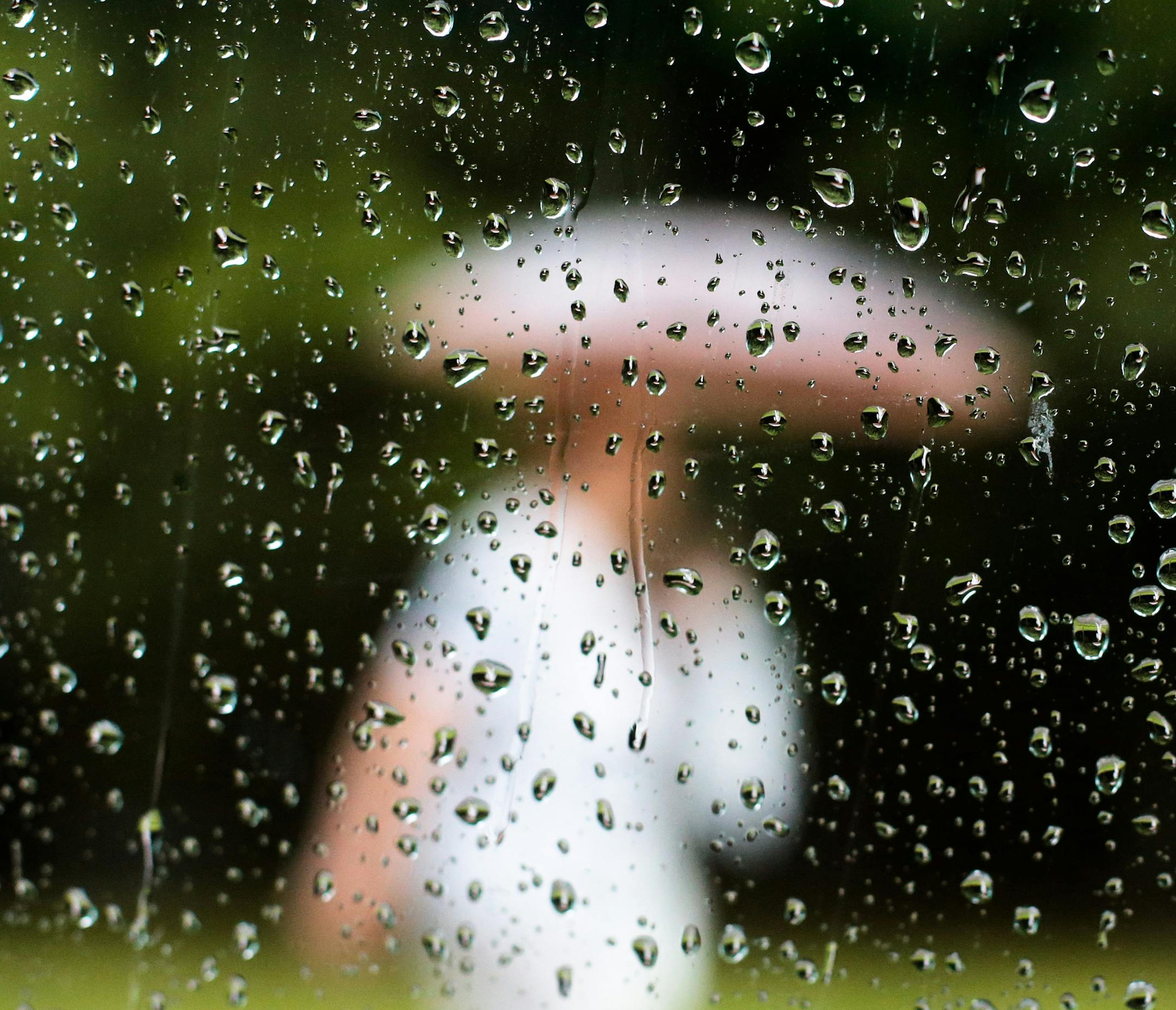 A woman with an umbrella , is photographed through a window with raindrops, in Berlin, Monday, July 7, 2014. Weather forecasts predict changeable weather for Germany. (AP Photo/Markus Schreiber) ORG XMIT: MIN2014071120192137