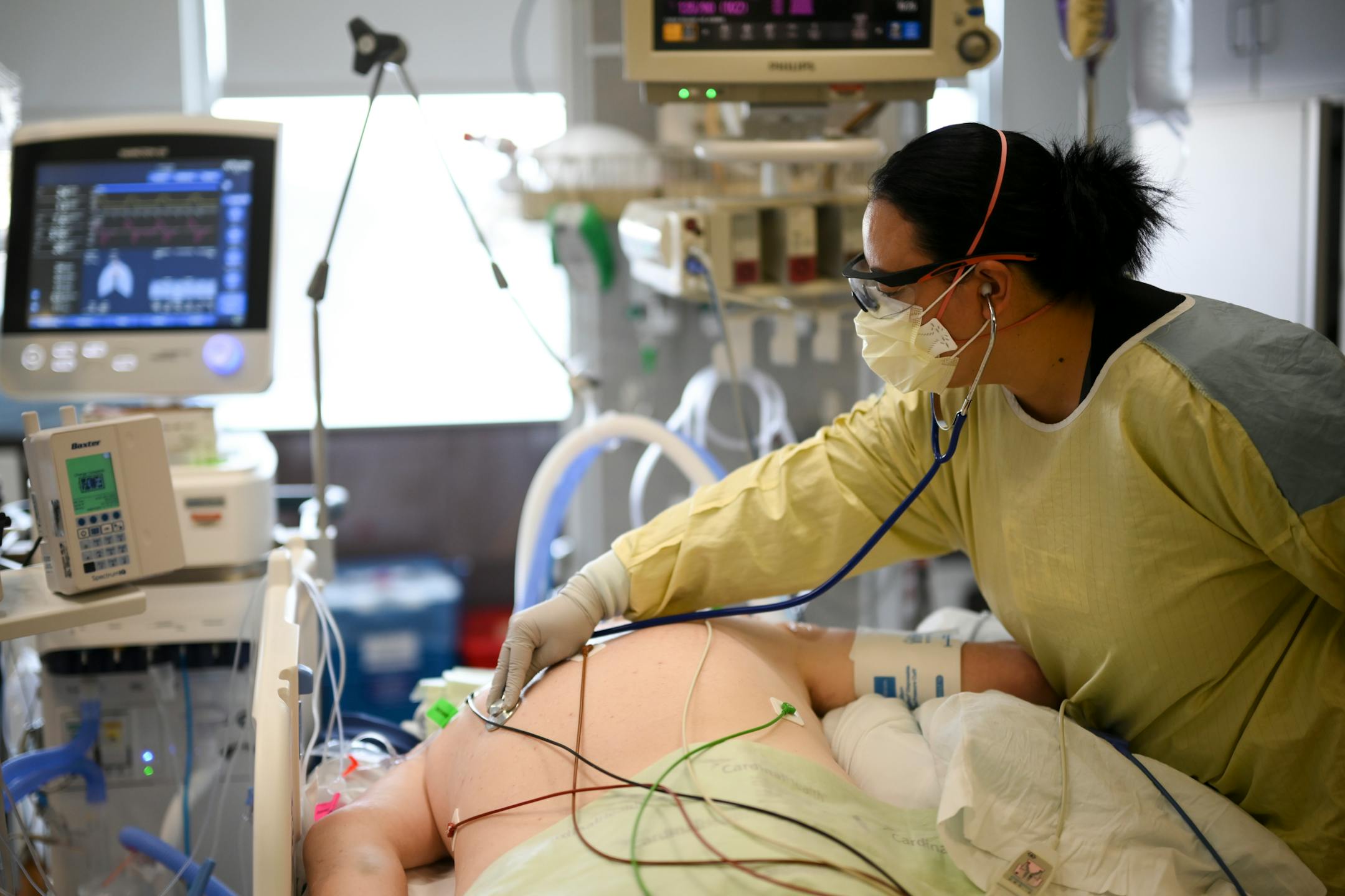 Respiratory therapist Lhakpa Tsamchoe listened to the breathing of an intubated COVID patient last month Tuesday, Feb. 8, 2022 at North Memorial Health Hospital in Robbinsdale, Minn. The patient was on 100-percent oxygen, which a fellow nurse notes is a bad sign for the survival of the patient.