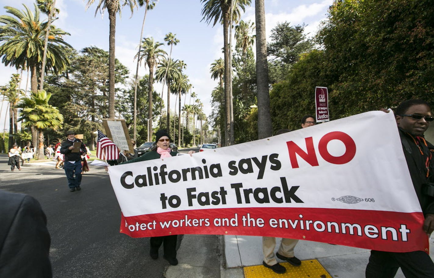 Los Angeles community members take to the streets of Beverly Hills to demand that Hillary Rodham Clinton oppose the Trans-Pacific Partnership (TPP) and Trade Promotion Authority (TPA) known as &#xec;The Fast Track,&#xee; in Beverly Hills, Calif., Thursday, May 7, 2015. Clinton is spending Thursday at three private fundraisers around LA, with tickets costing $2,700 per person. The front-runner for the Democratic nomination is on a three-day swing through California. (AP Photo/Damian Dovarganes) O