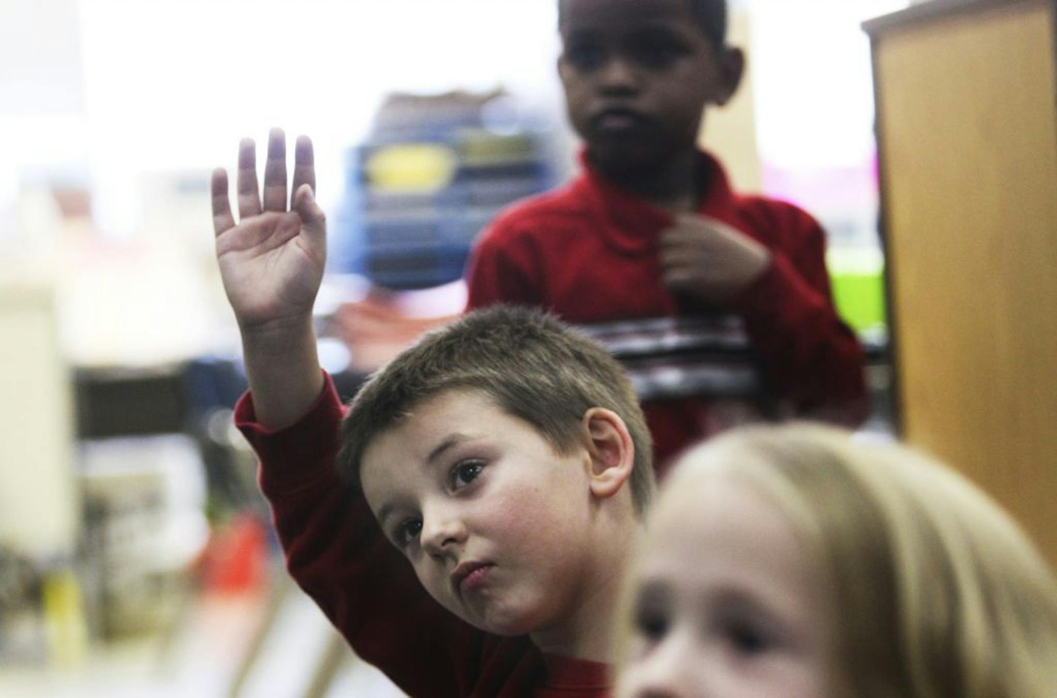 Kindergarten student Mason Greeman raises his hand to answer a question in Heather West's Scenic Heights Elementary School kindergarten class Thursday, Nov. 8, 2012, in Minnetonka, MN. Looking on is Ridwan Ahmed.