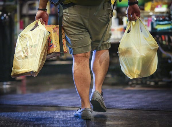 A man carried plastic bags of groceries out of Kowalski's in Uptown in Minneapolis, Minn., on Thursday, July 23, 2015.