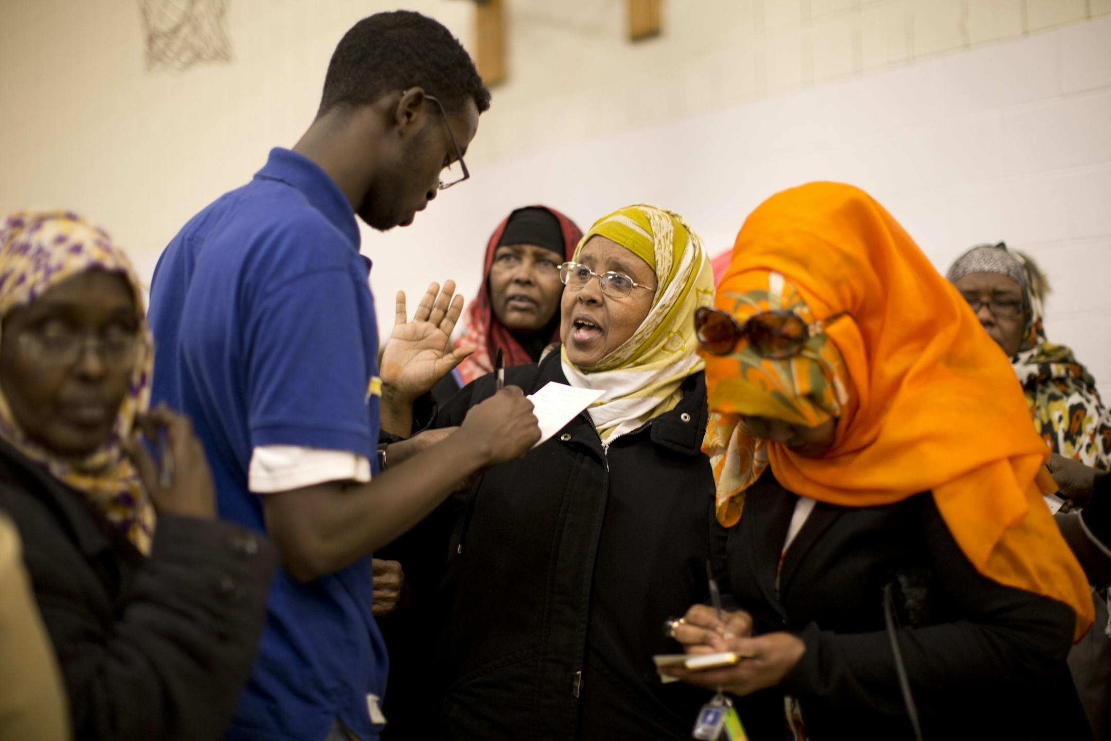 Hundreds of people crowded into the gym at the Bryan Coyle Center to participate in the Ward 6, Precinct 3 caucus on April 16 in Minneapolis. Mohamed Jama, in blue, passed out ballot cards and assisted women who wanted to be elected to the Ward 6 convention.