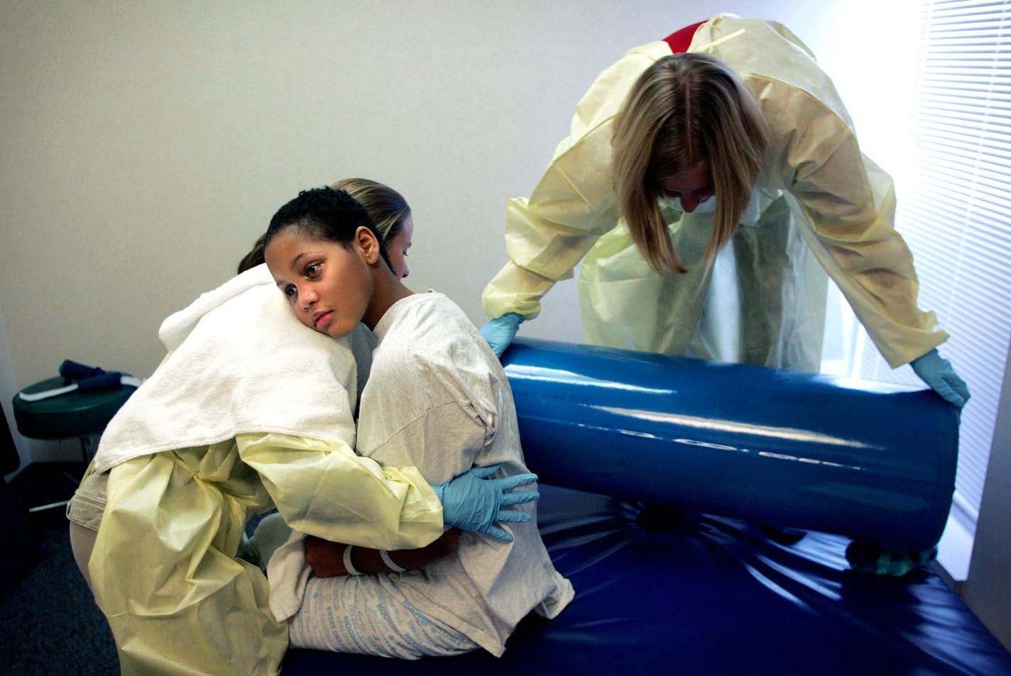 Twelve-year-old Vernice Hall, center, rested against physical therapist Amy Schulz, left, while therapist Karen Cepress placed a booster behind Hall to support her as she sat up. Hall, who was shot in the head outside her home two months ago, is starting physical therapy at Gillette Children's Hospital.