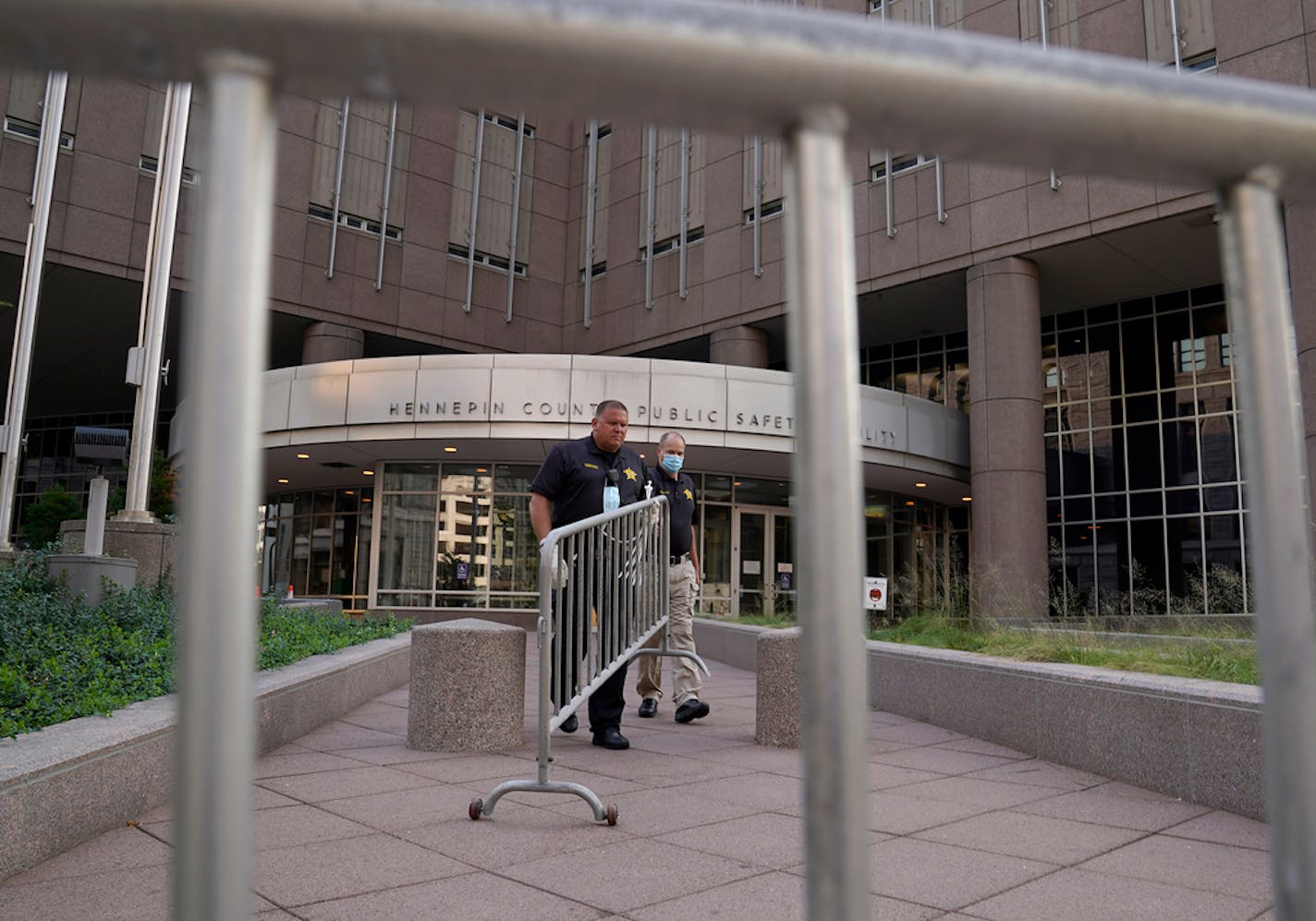 Law enforcement officers outside the Hennepin County Public Safety Facility Tuesday morning, where a demonstration in response to the police shooting of a black man in Kenosha, Wisc., turned violent late Monday, where protesters broke front entry door windows to the jail.]