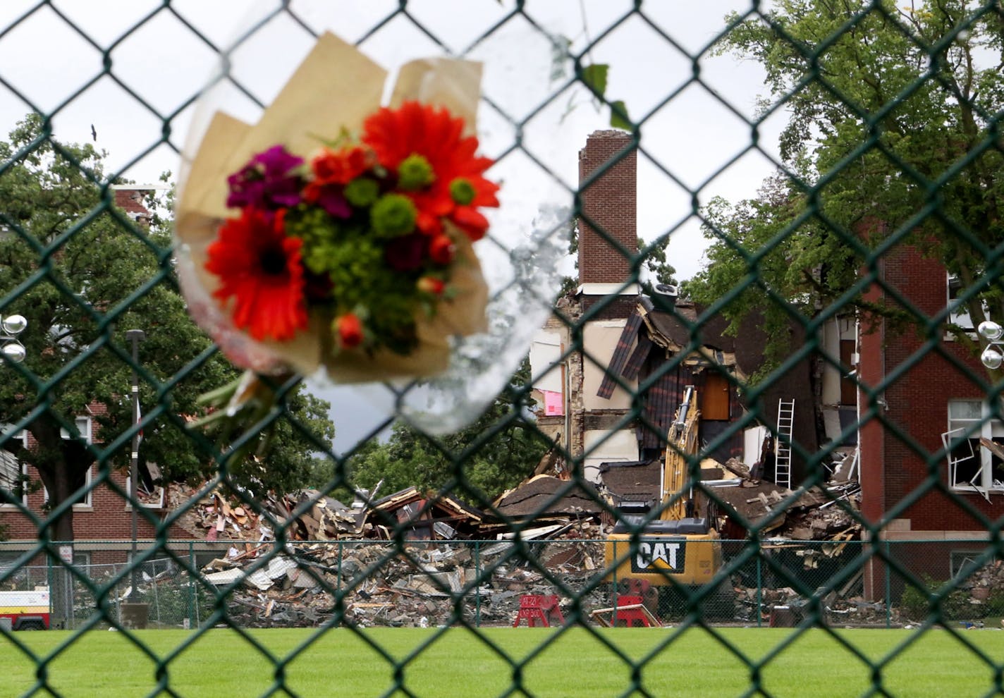 Flowers adorn a fence a day after an explosion and building collapse at Minnehaha Academy that left two dead and several injured.