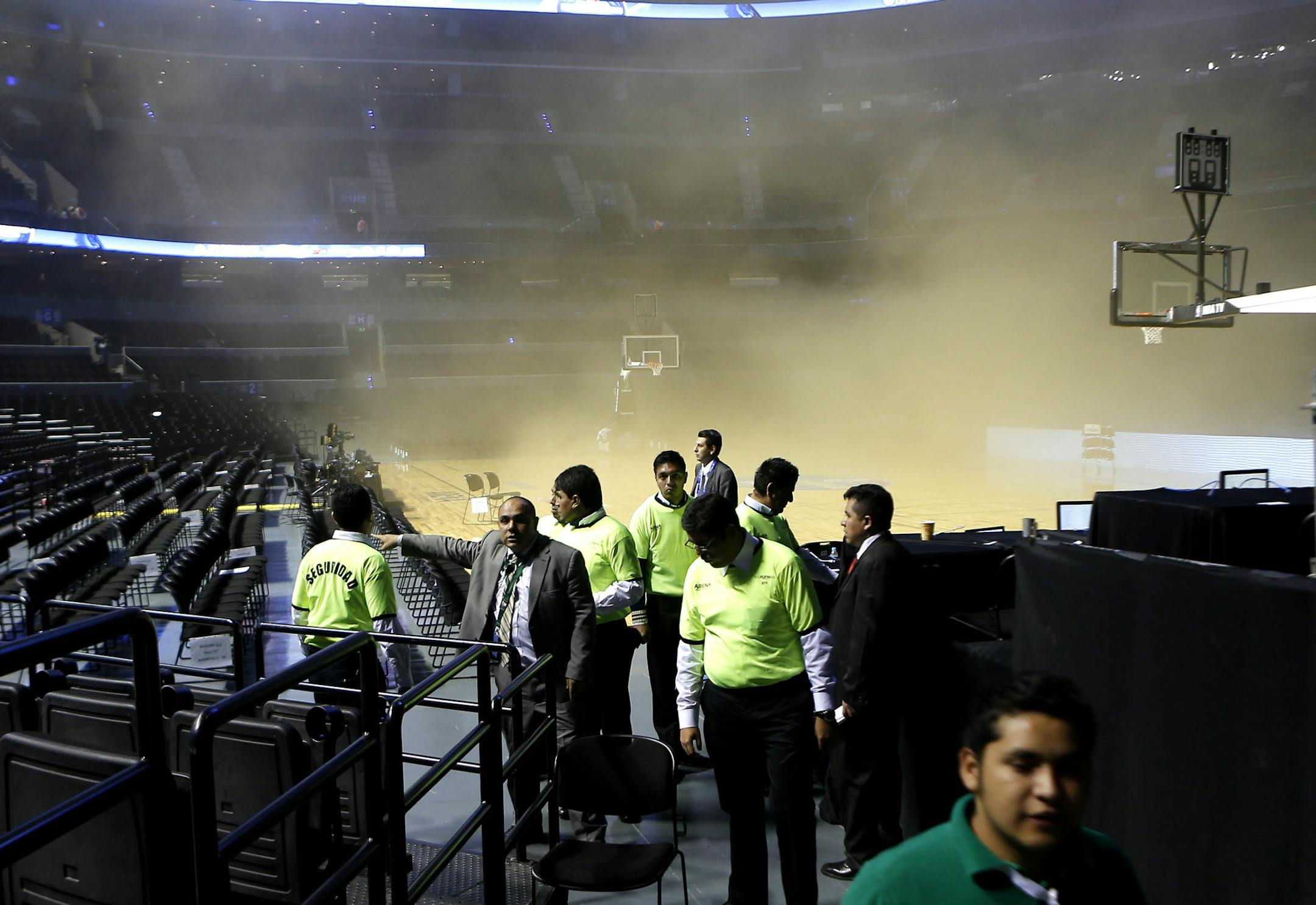 People leave as smoke engulfs the basketball court during a regular season NBA match between the Minnesota Timberwolves and the San Antonio Spurs in Mexico City, Wednesday, Dec. 4, 2013. NBA spokeswoman Sharon Lima says the smoke was coming from a generator fire outside the arena. There was no word yet if the start of the game will be delayed. (AP Photo/Eduardo Verdugo) ORG XMIT: MXEV104