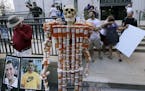 A skeleton of pill bottles stands with protesters outside a courthouse on Friday, Aug. 2, 2019, in Boston, where a judge was to hear arguments in Mass