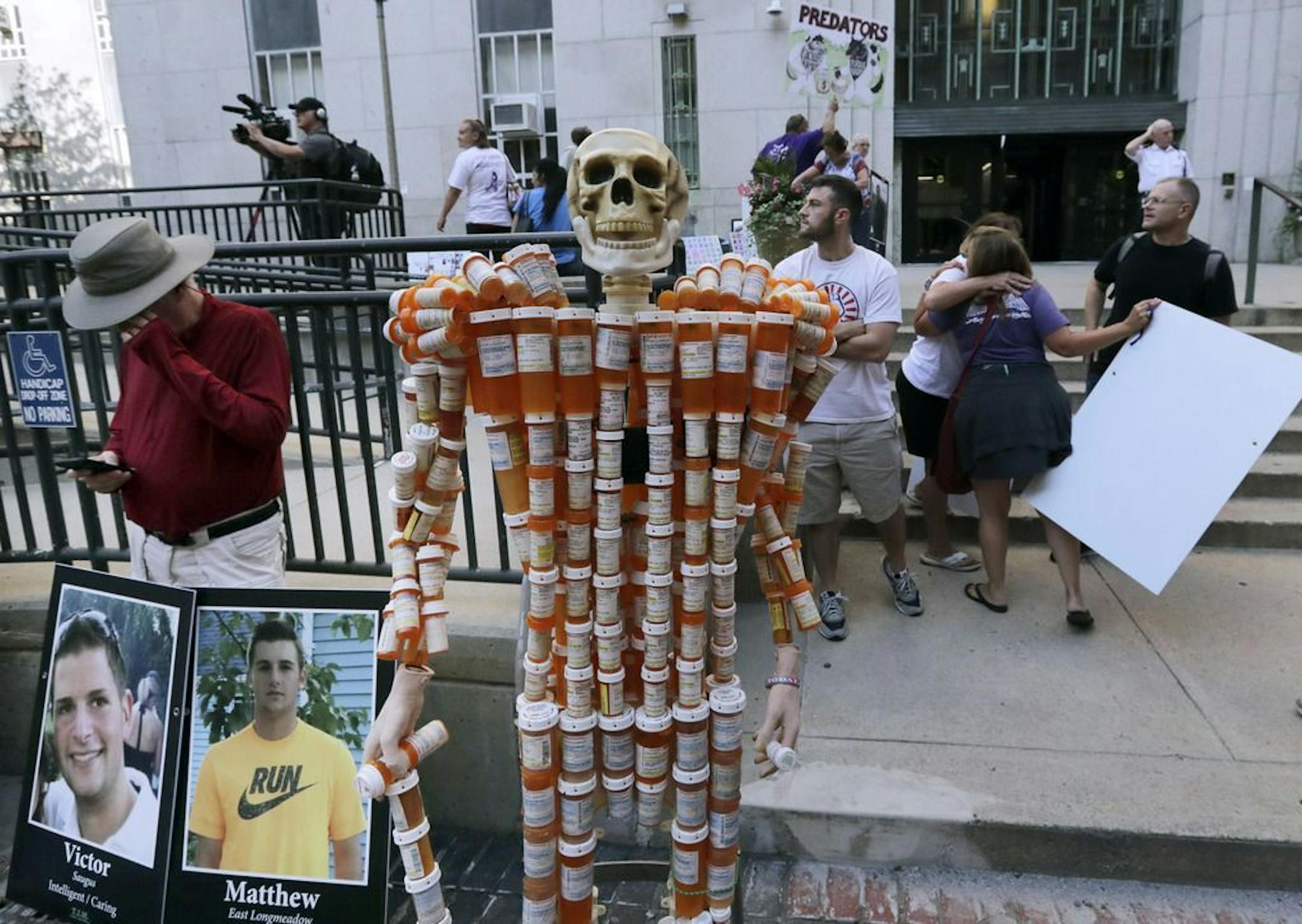 A skeleton of pill bottles stands with protesters outside a courthouse on Friday, Aug. 2, 2019, in Boston, where a judge was to hear arguments in Massachusetts' lawsuit against Purdue Pharma over its role in the national drug epidemic. The skeleton was created by Frank Huntley, of Worcester, Mass., from prescriptions he said he received while addicted to opioids. Organizers of the protest said they wanted to continue to put pressure on the Connecticut pharmaceutical company and the Sackler famil
