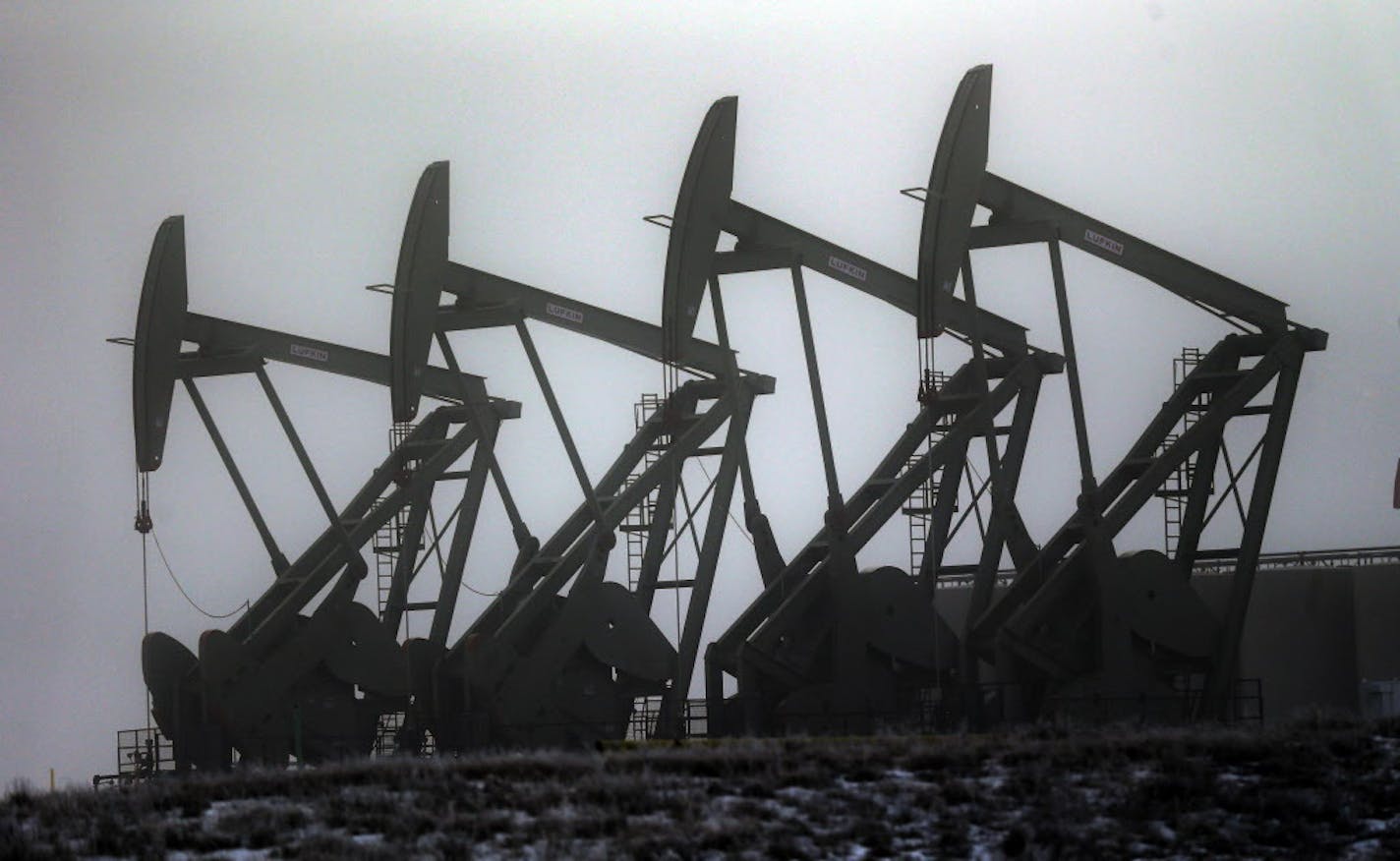 FILE - In this Dec. 19, 2014, file photo, oil pump jacks work in unison in Williston, N.D. In the heart of North Dakota's oil patch, there are hundreds of more jobs than takers. No longer is it easy to find a hotel room or a table at a restaurant. More than two years after the state's unprecedented oil bonanza fizzled, North Dakota is experiencing a sort of boomlet with an increase in drilling that has brought oil production back up to more than 1 million barrels daily. (AP Photo/Eric Gay, File)