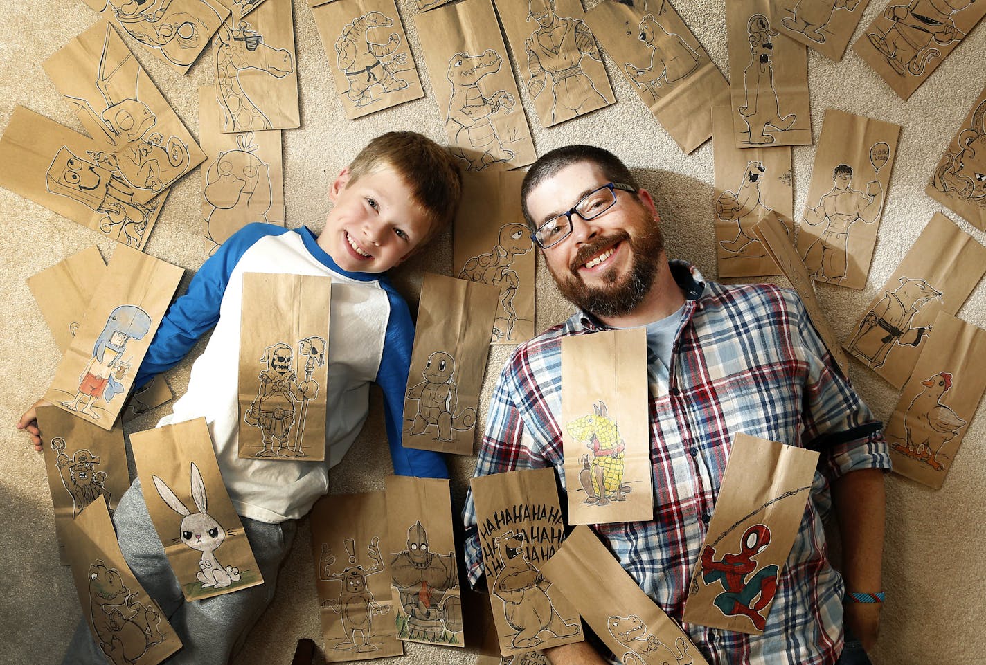 Bryan Dunn and his son Rowan, 7, photographed with some finished and unfinished lunch bags drawings at their home in Eden Prairie, Minn. ] CARLOS GONZALEZ cgonzalez@startribune.com - September 10, 2014, Eden Prairie, Minn., Two local dads send their kids off to schools each days toting lunch bags that they've illustrated. Bryan Dunn, a graphic illustrator, send his kids off to school with fancifully-illustrated lunch bags.