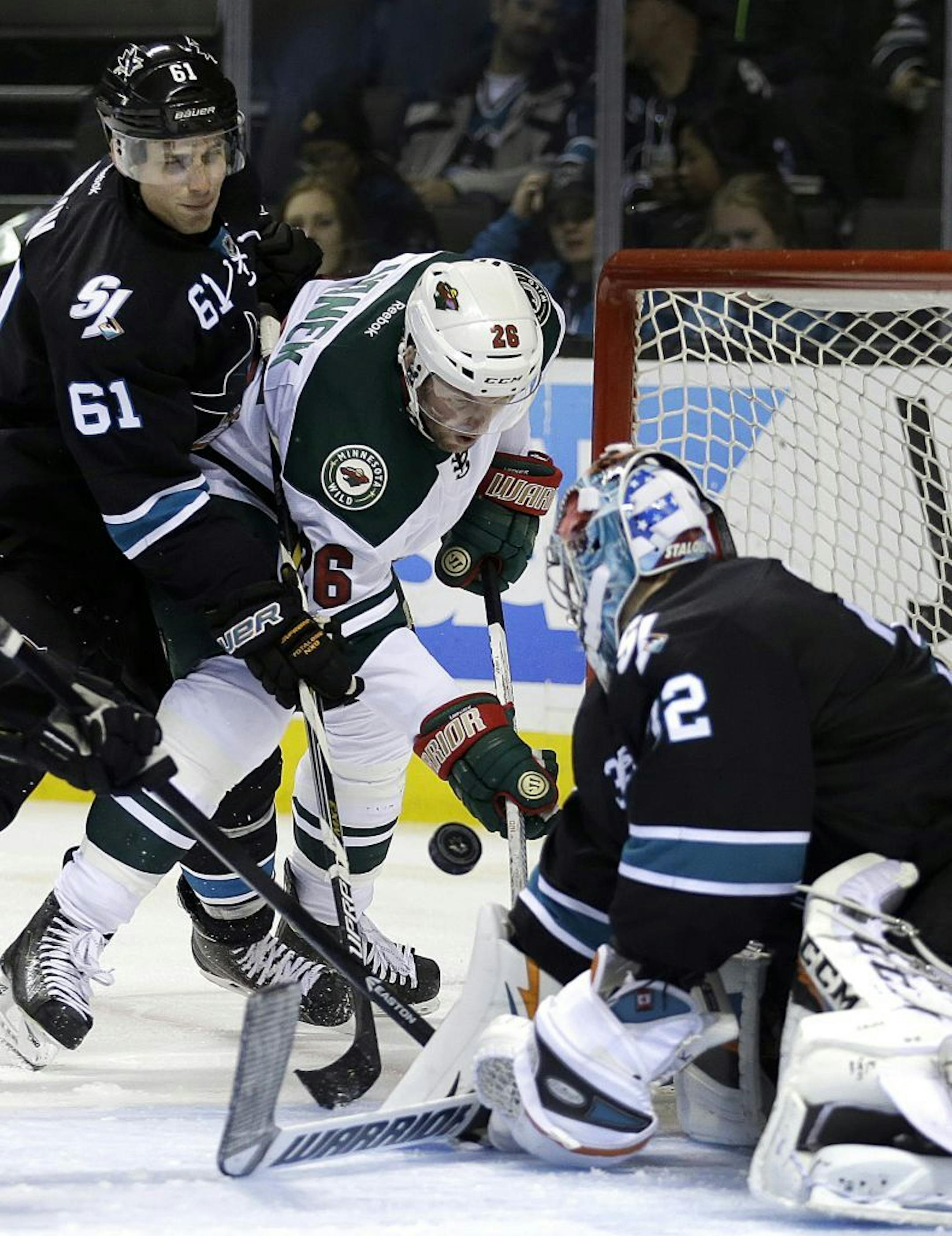 San Jose Sharks goalie Alex Stalock, right, defends against a shot by Minnesota Wild left wing Thomas Vanek (26) during the second period of an NHL hockey game Thursday, Dec. 11, 2014, in San Jose, Calif. At left is Sharks' Justin Braun (61).