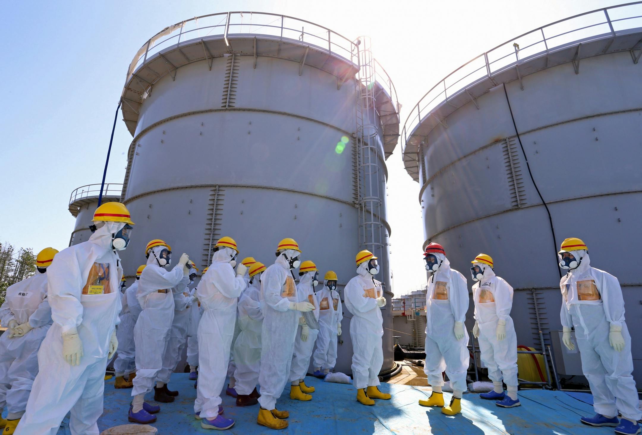 Japanese Prime Minister Shinzo Abe, third right, wearing a red helmet, is briefed about tanks containing radioactive water during his tour of to the tsunami-crippled Fukushima plant on Sept. Sept. 19, 2013.