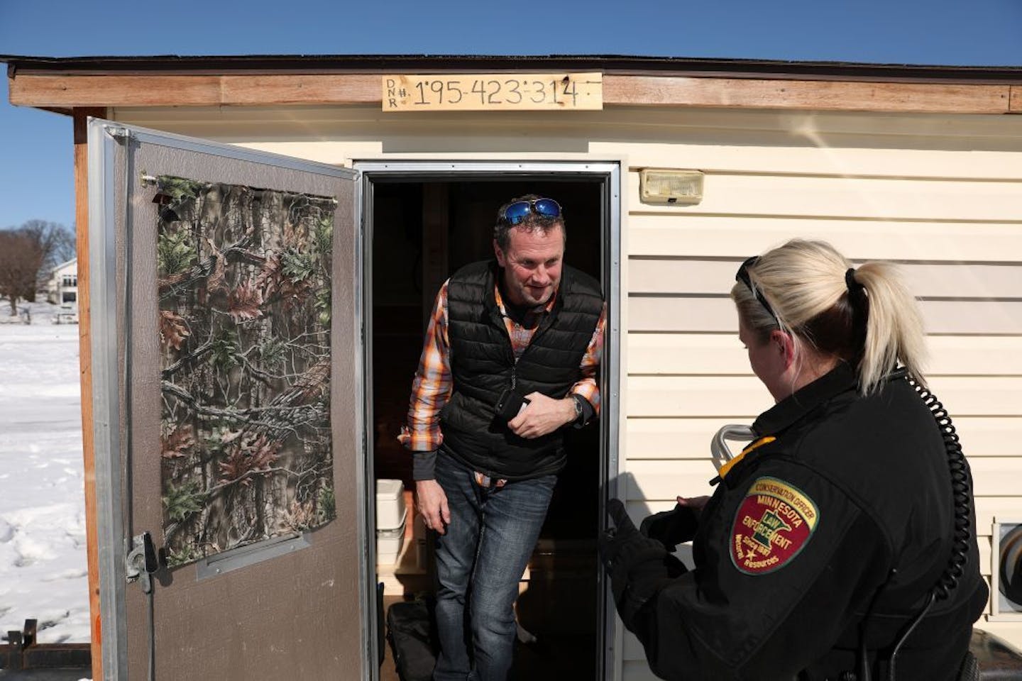 Minnesota Department of Natural Resources conservation officer Leah Weyandt talked with angler Darrin Stuhr of Eden Prairie about the upcoming deadline to remove ice fishing shelters Thursday at Lake Minnetonka.